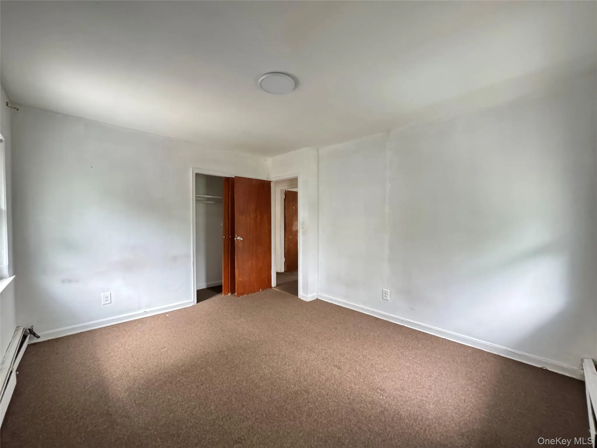 Carpeted empty room with a baseboard radiator and baseboard heating Carpeted empty room with a baseboard radiator and baseboard heating