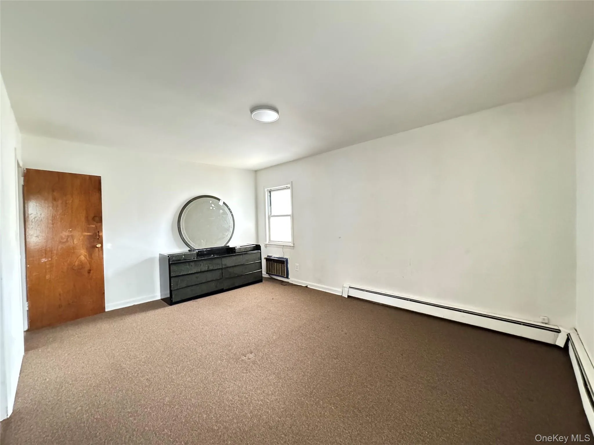 Unfurnished bedroom with a baseboard radiator and carpet floors Unfurnished bedroom with a baseboard radiator and carpet floors