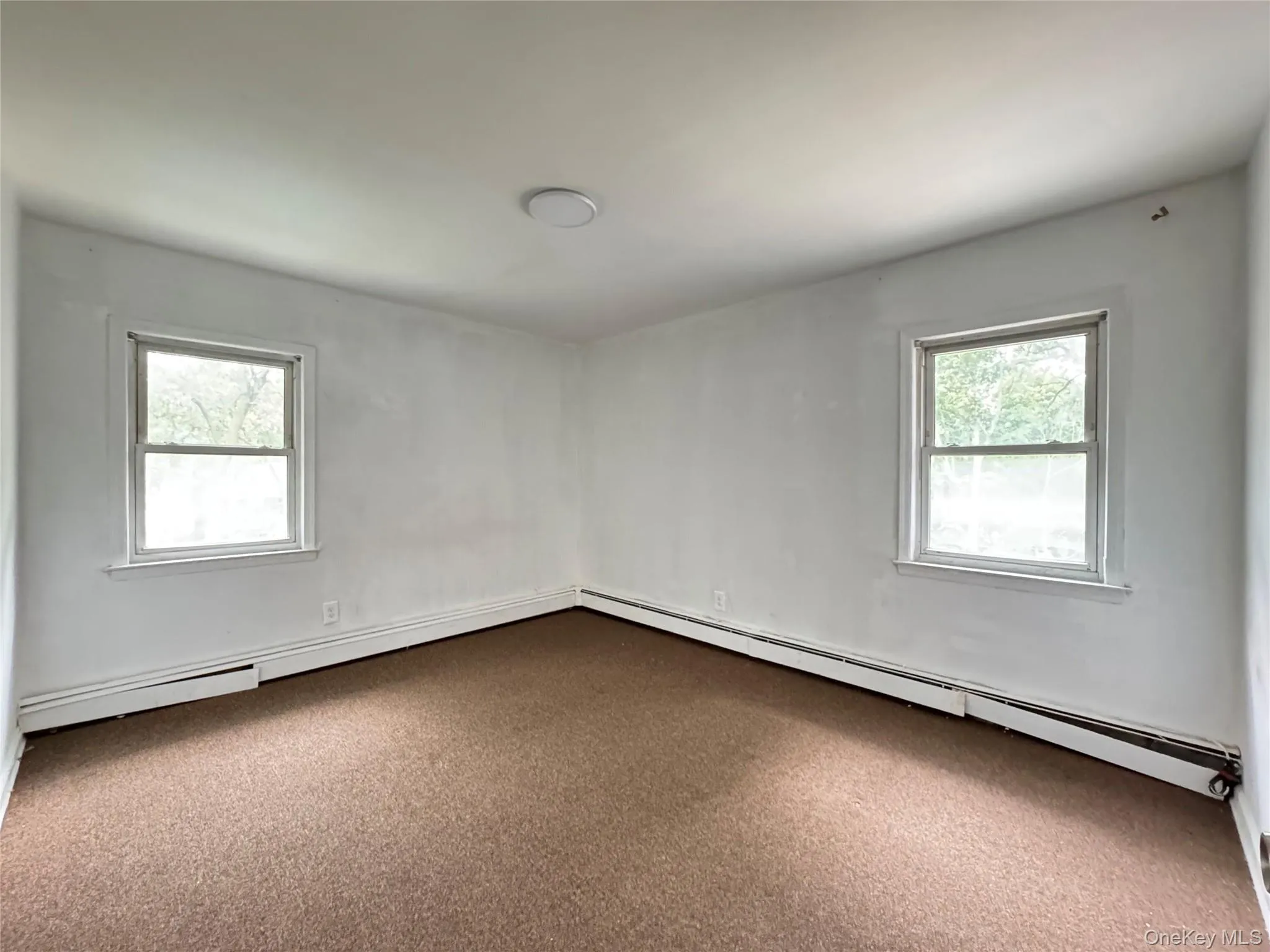 Carpeted empty room featuring a baseboard heating unit Carpeted empty room featuring a baseboard heating unit