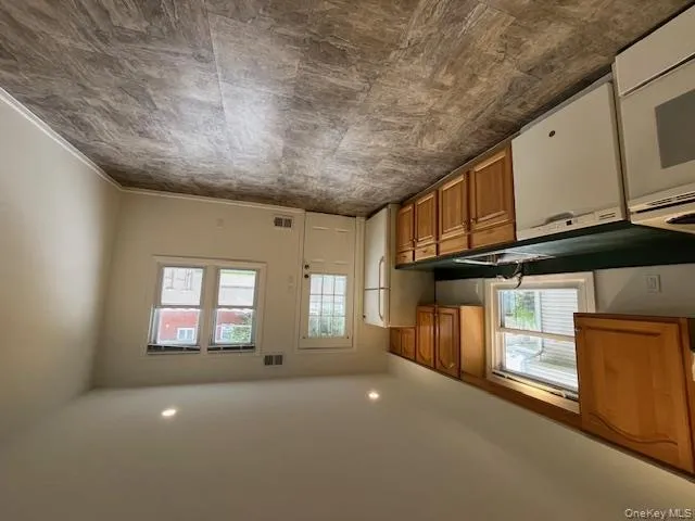 Kitchen featuring brown cabinetry, dark countertops, range, refrigerator, and dishwasher Kitchen featuring brown cabinetry, dark countertops, range, refrigerator, and dishwasher