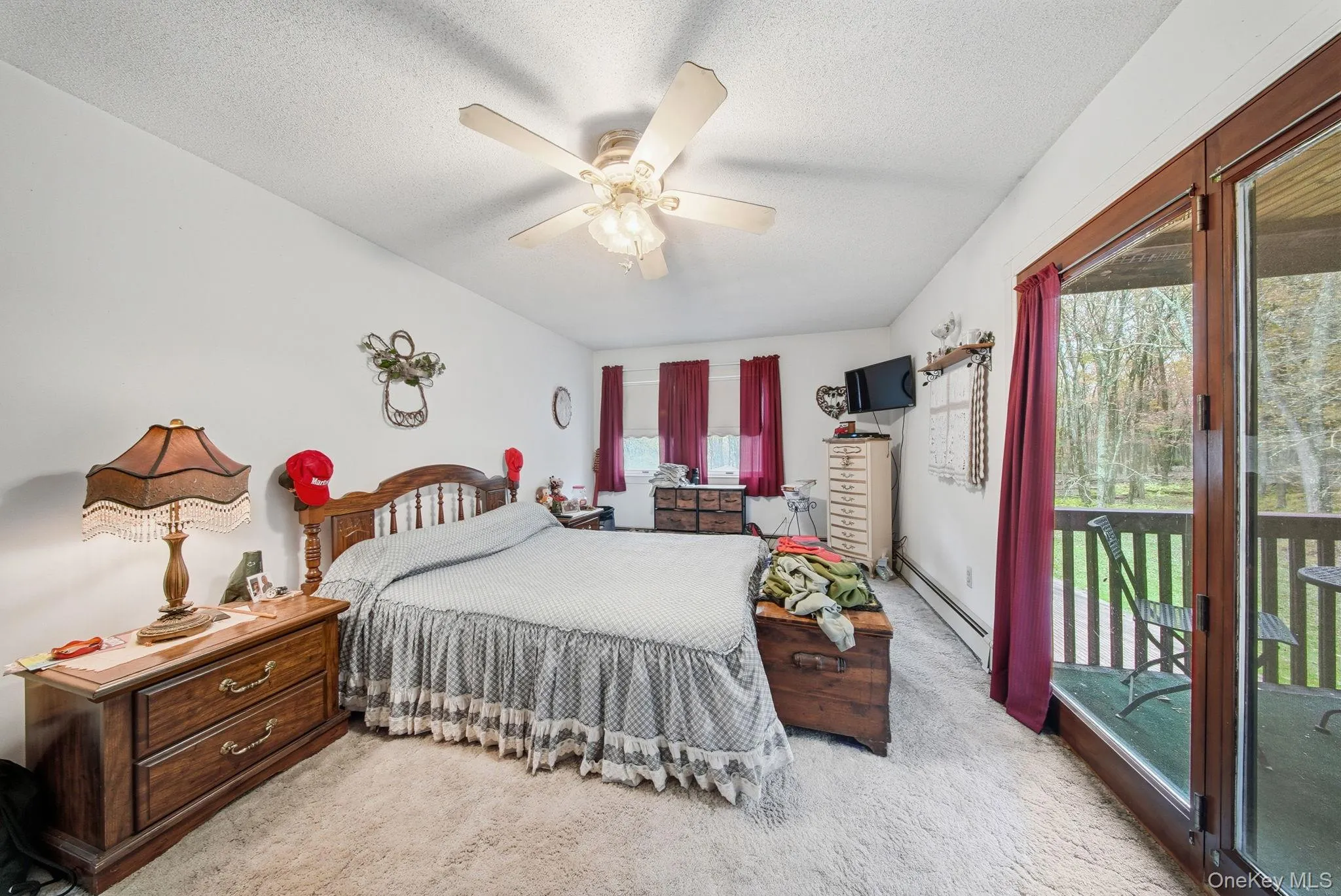 Bedroom featuring access to outside, a baseboard heating unit, light colored carpet, a ceiling fan, and a textured ceiling Bedroom featuring access to outside, a baseboard heating unit, light colored carpet, a ceiling fan, and a textured ceiling