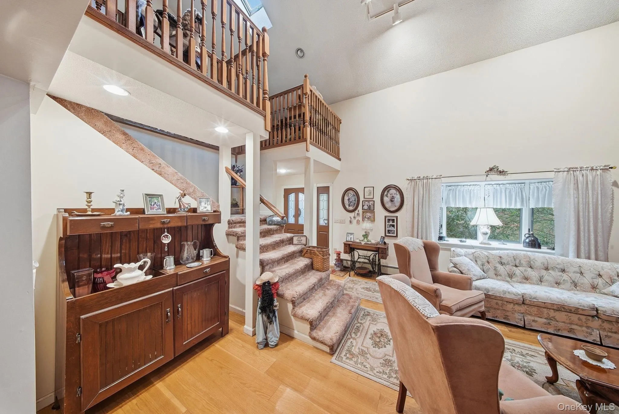 Living room featuring a towering ceiling, light wood finished floors, and stairs Living room featuring a towering ceiling, light wood finished floors, and stairs