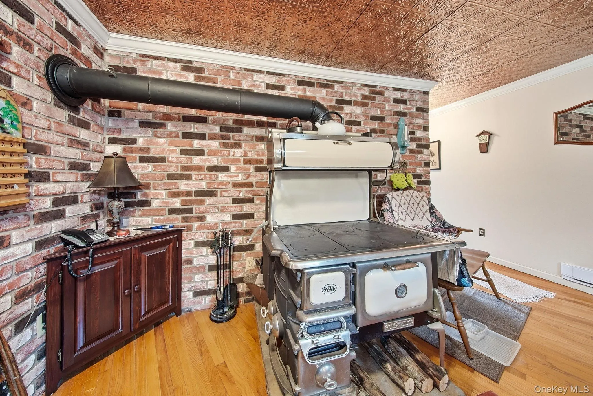 Kitchen with crown molding, light wood-style floors, an ornate ceiling, brick wall, and dark brown cabinetry Kitchen with crown molding, light wood-style floors, an ornate ceiling, brick wall, and dark brown cabinetry