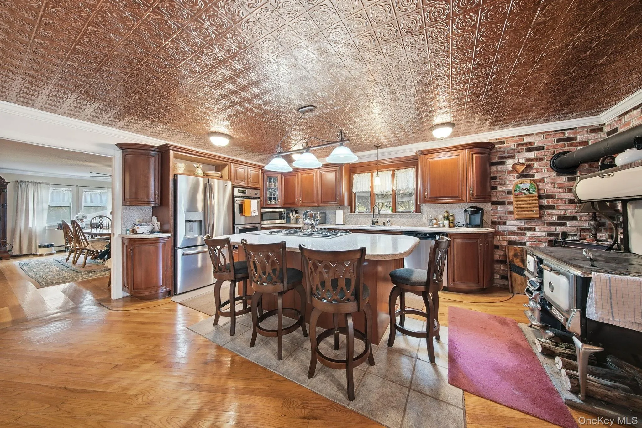 Kitchen featuring ornamental molding, a kitchen island, a kitchen bar, an ornate ceiling, and decorative light fixtures Kitchen featuring ornamental molding, a kitchen island, a kitchen bar, an ornate ceiling, and decorative light fixtures