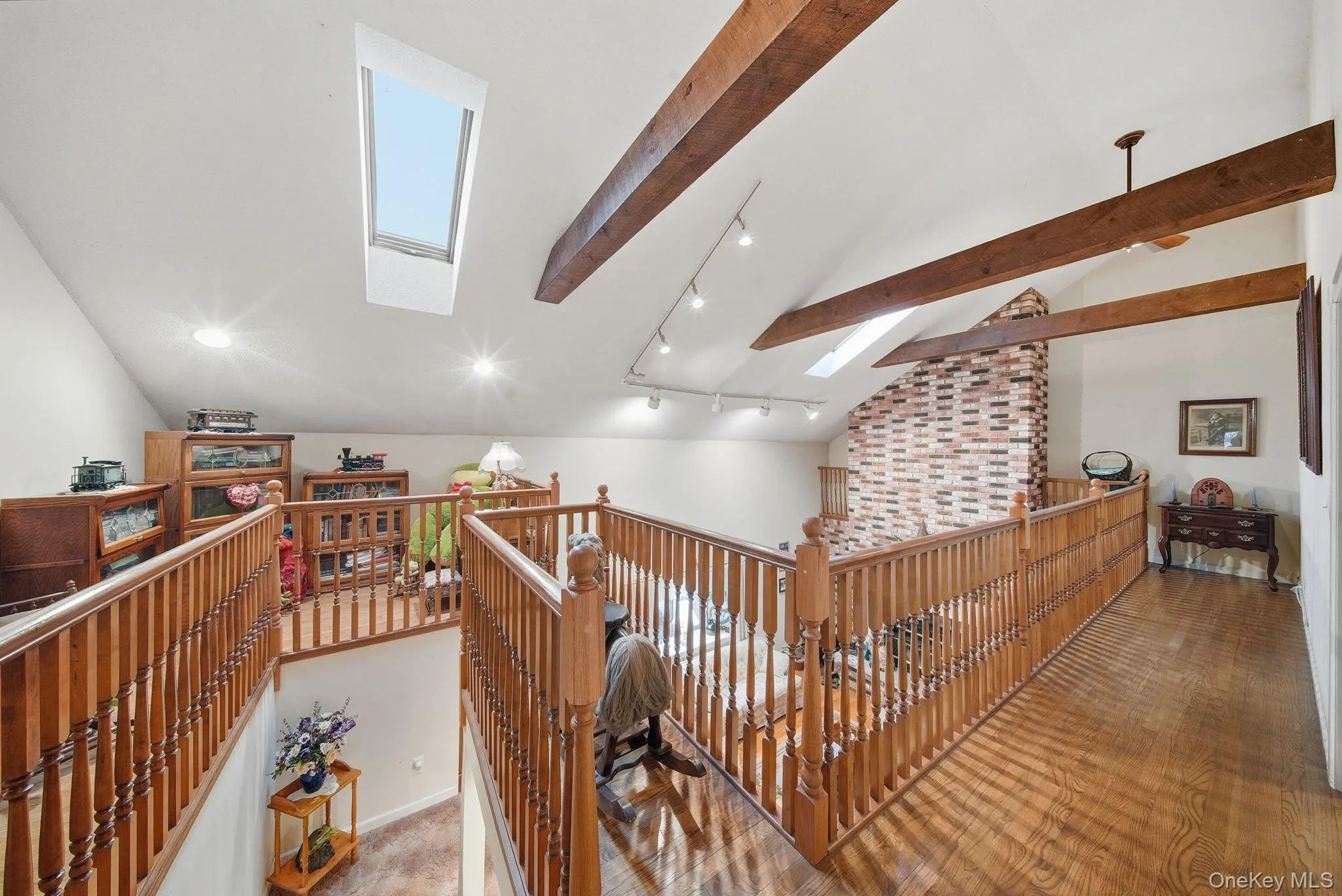 Corridor with a skylight, track lighting, an upstairs landing, and wood finished floors Corridor with a skylight, track lighting, an upstairs landing, and wood finished floors
