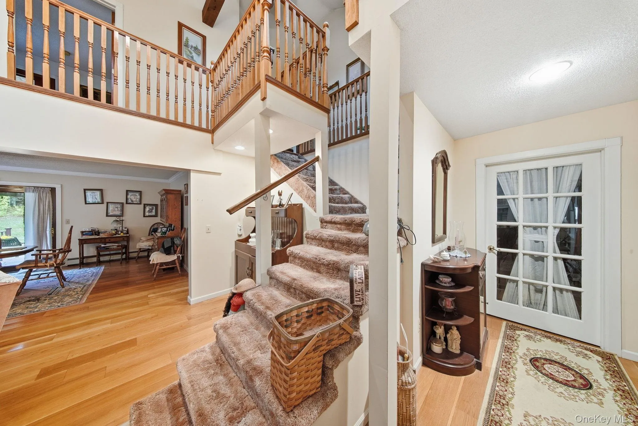 Staircase featuring wood finished floors, a towering ceiling, and baseboard heating Staircase featuring wood finished floors, a towering ceiling, and baseboard heating