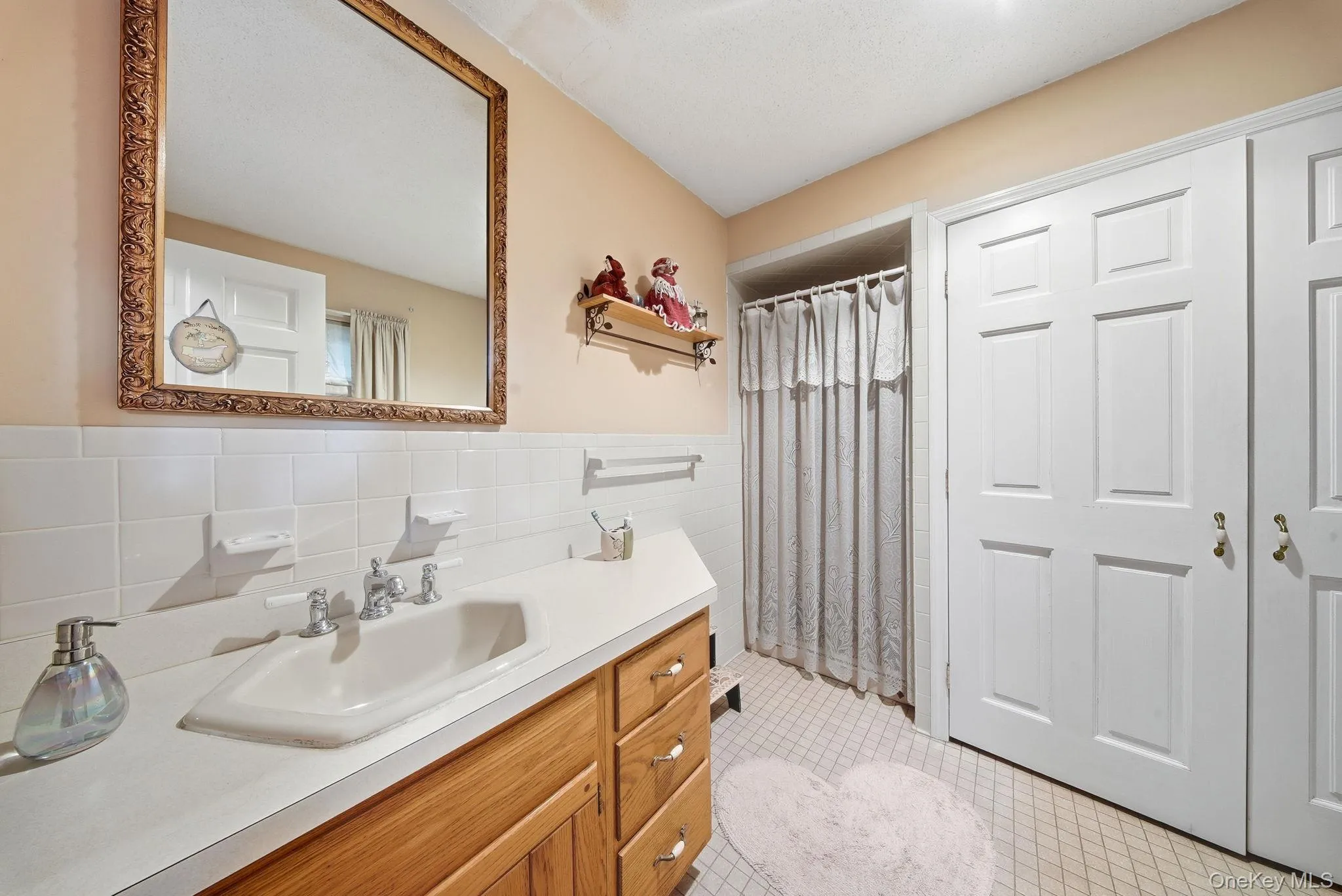 Full bathroom featuring vanity, a shower with curtain, tile walls, and light tile patterned flooring Full bathroom featuring vanity, a shower with curtain, tile walls, and light tile patterned flooring