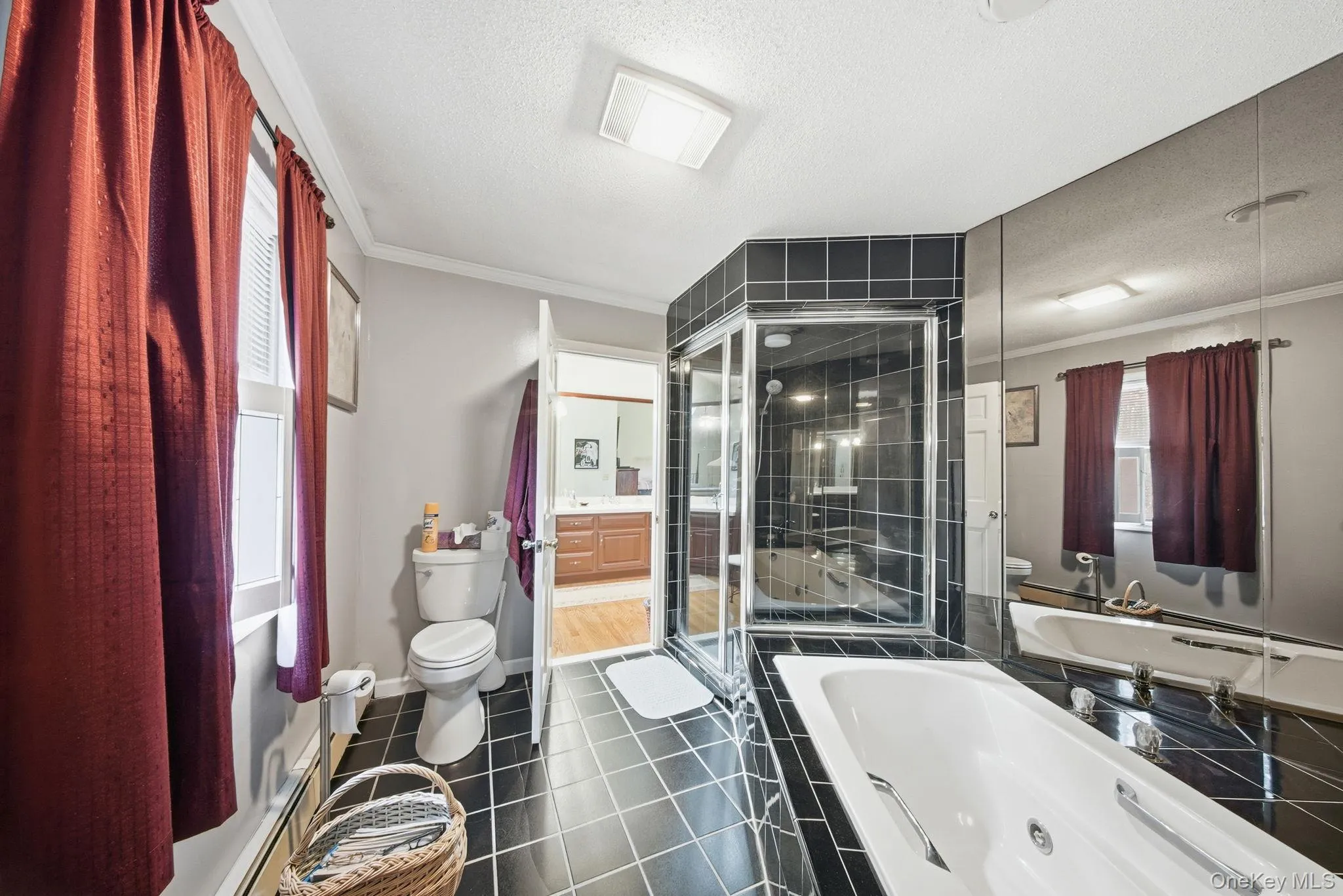 Full bathroom with a textured ceiling, dark tile patterned floors, a jetted tub, ornamental molding, and a stall shower Full bathroom with a textured ceiling, dark tile patterned floors, a jetted tub, ornamental molding, and a stall shower