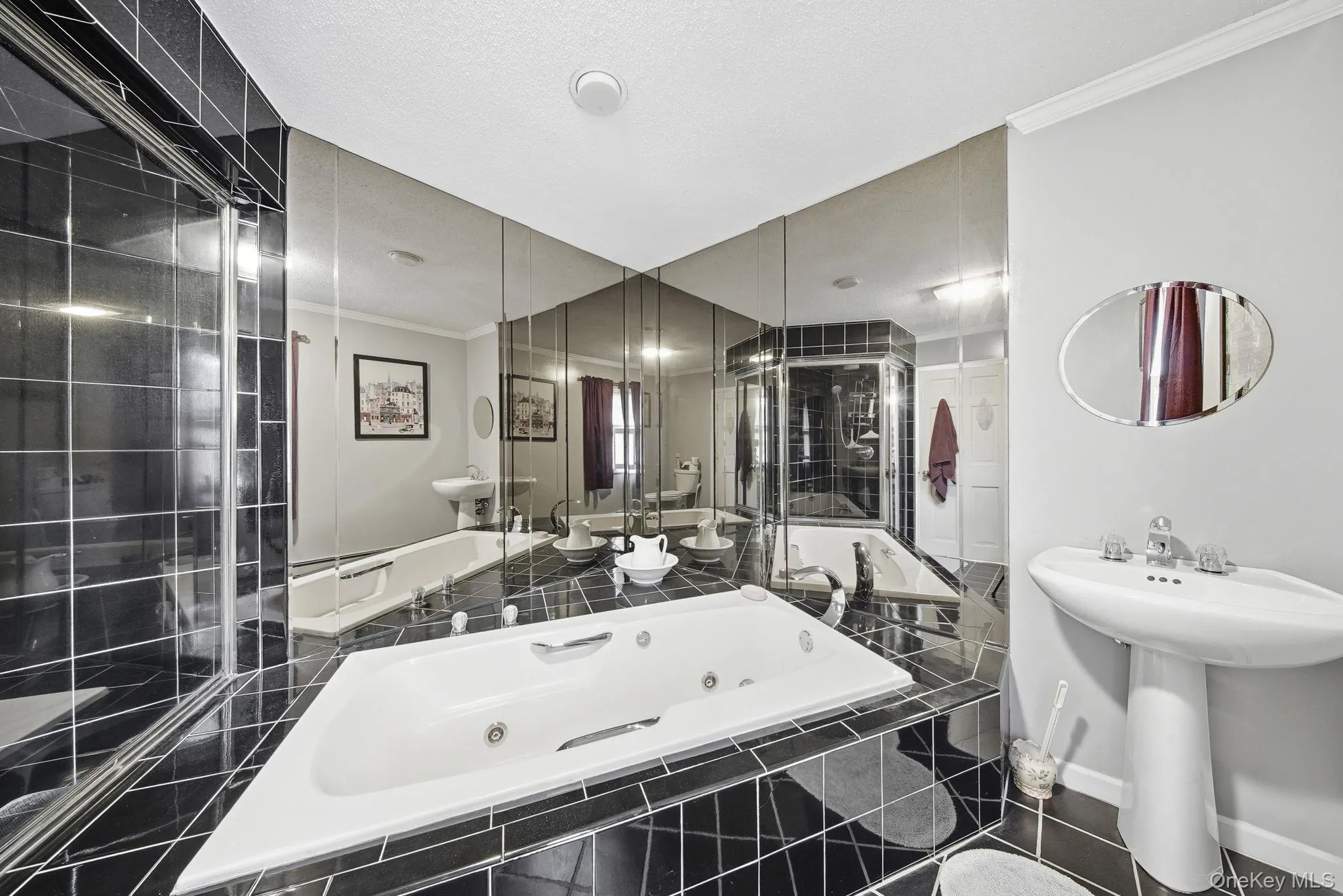 Bathroom featuring crown molding, a jetted tub, and dark tile patterned floors Bathroom featuring crown molding, a jetted tub, and dark tile patterned floors