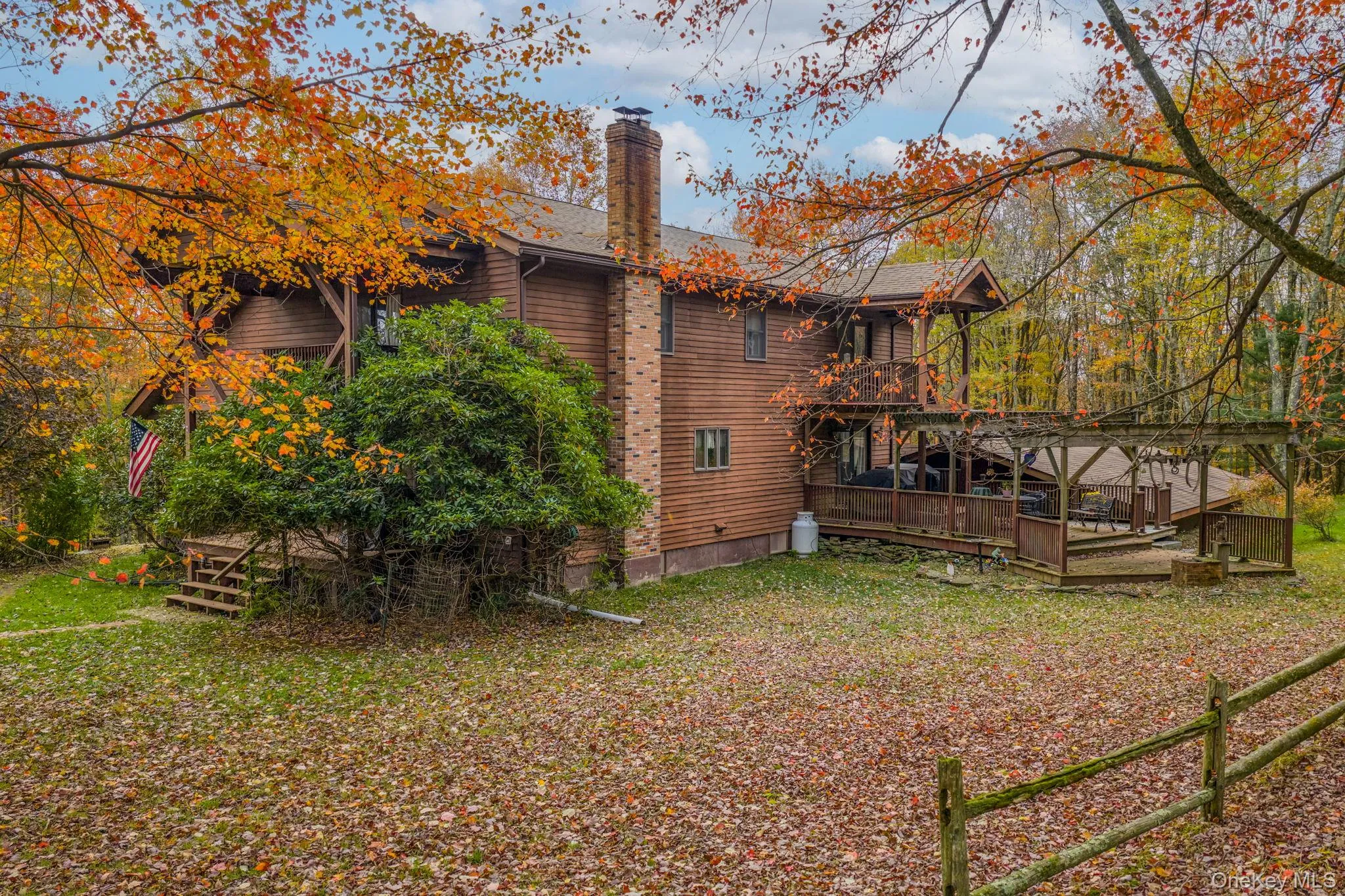 Rear view of house featuring a chimney, a wooden deck, and a yard Rear view of house featuring a chimney, a wooden deck, and a yard