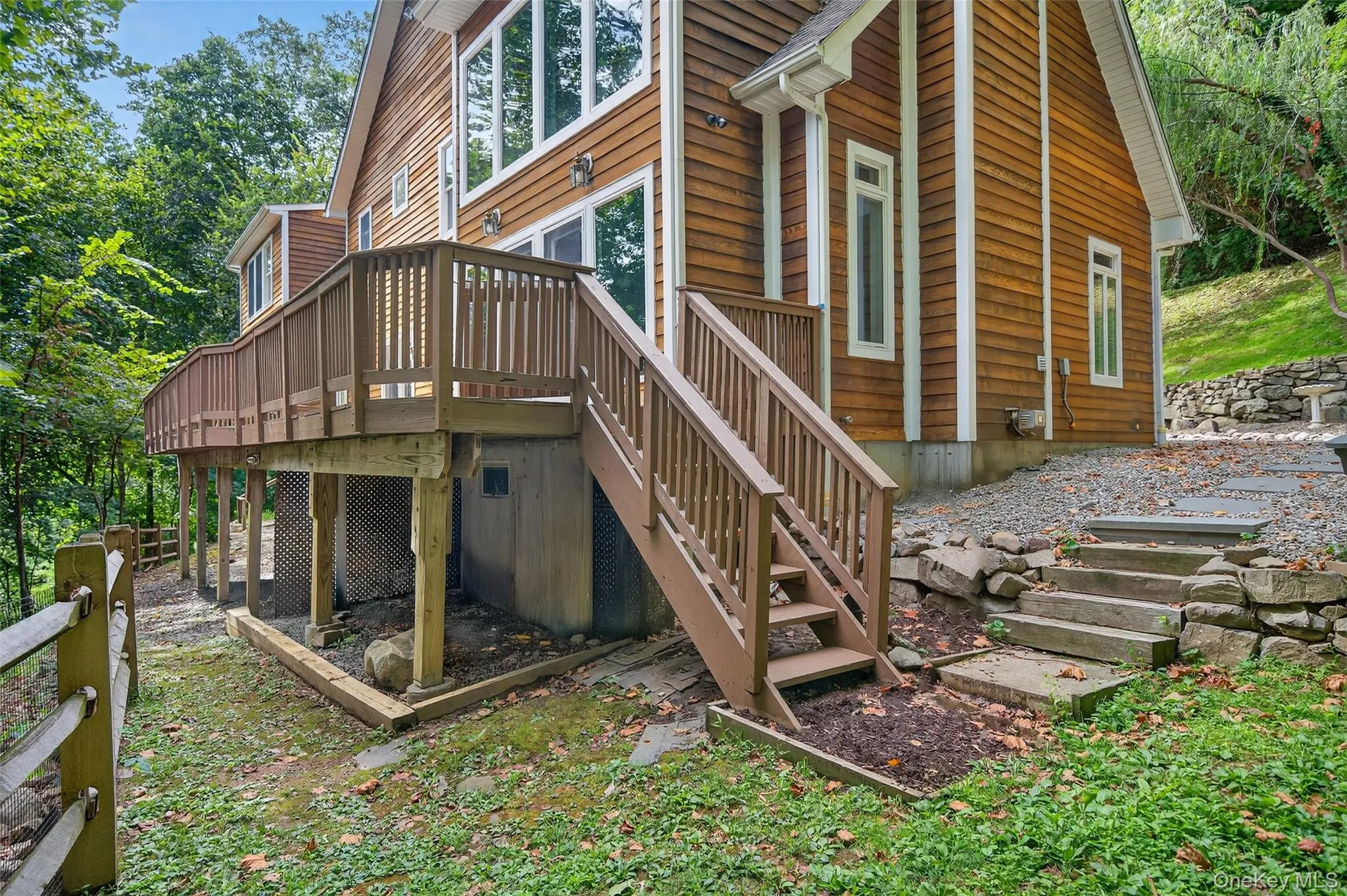 Back of property featuring stairs, a wooden deck, and a wooded view Back of property featuring stairs, a wooden deck, and a wooded view