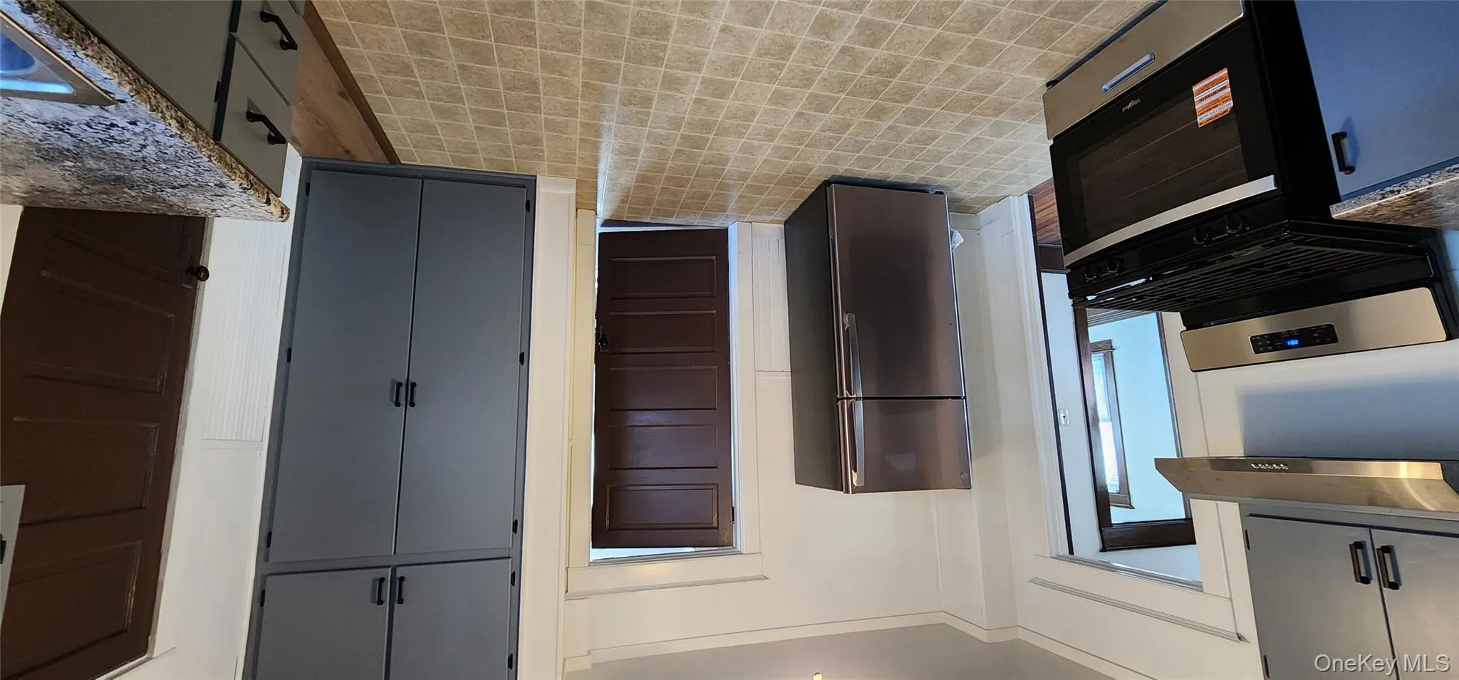 Kitchen featuring range, fridge, gray cabinets, and exhaust hood Kitchen featuring range, fridge, gray cabinets, and exhaust hood
