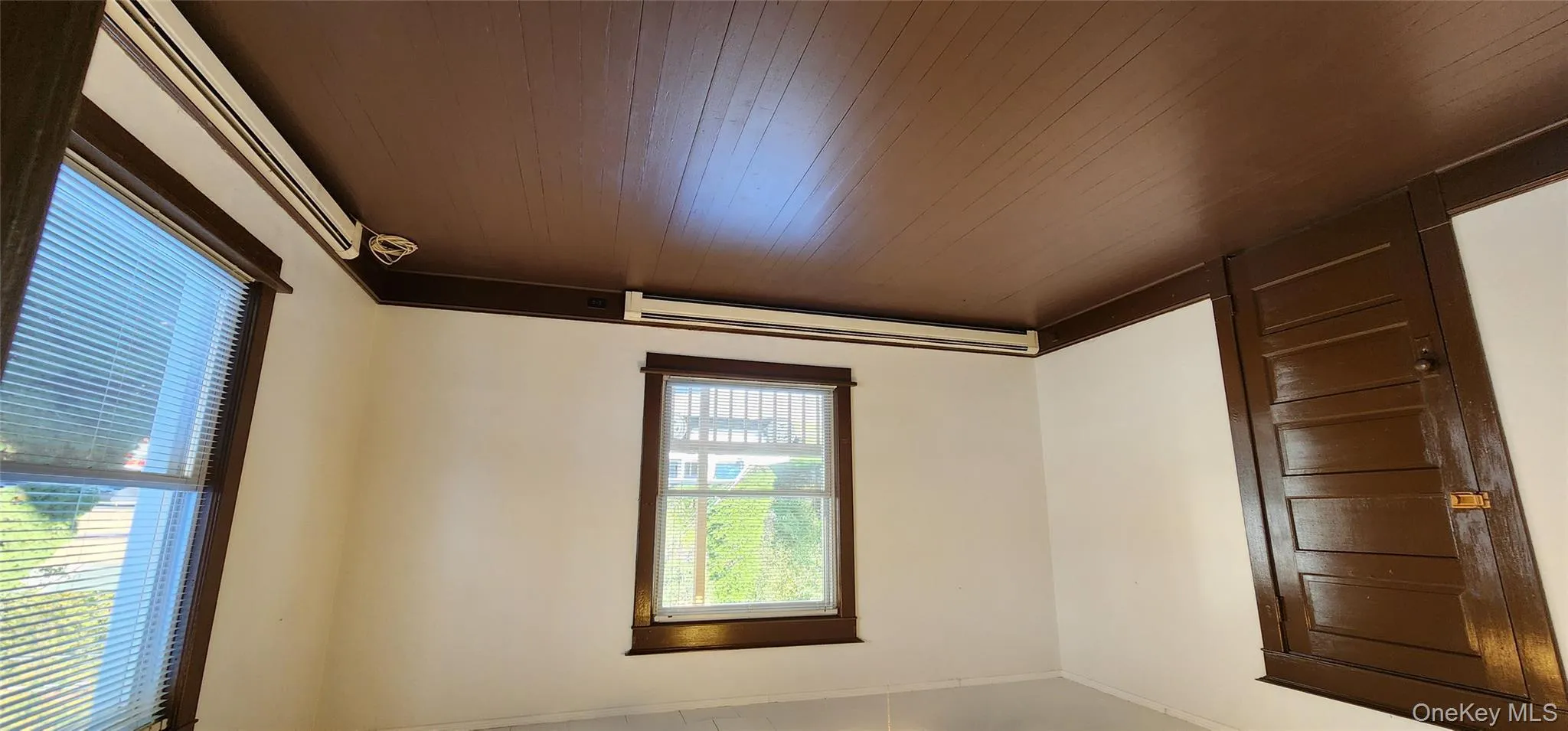 Empty room featuring a baseboard radiator, dark wood-style floors, and crown molding Empty room featuring a baseboard radiator, dark wood-style floors, and crown molding