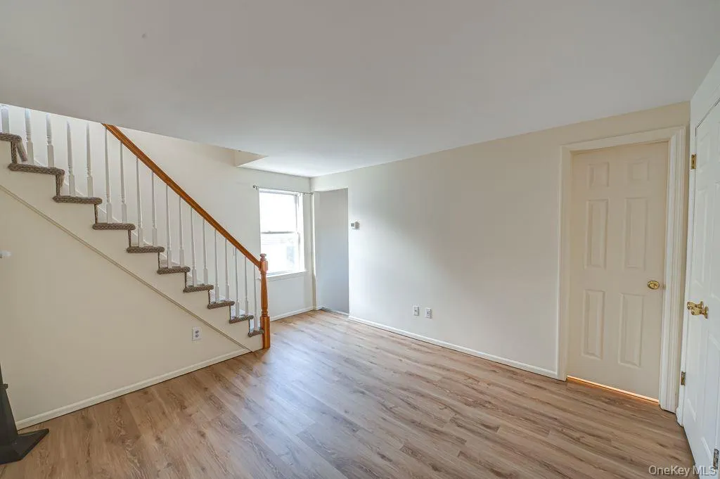 Unfurnished living room featuring stairway to loft and light wood-style floors Unfurnished living room featuring stairway to loft and light wood-style floors