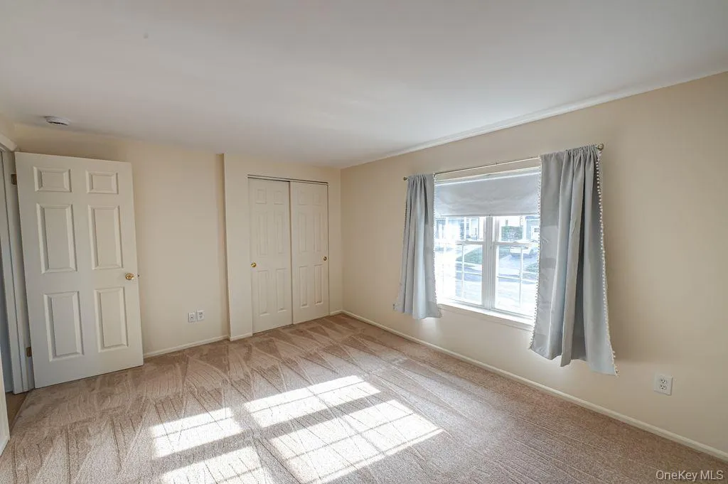 Unfurnished bedroom with light colored new carpet and a closet Unfurnished bedroom with light colored new carpet and a closet