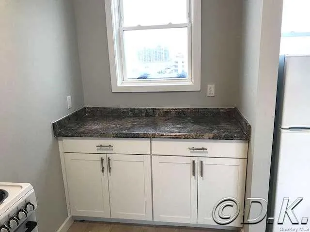 Kitchen view of white cabinetry, white appliances, and dark stone counters Kitchen view of white cabinetry, white appliances, and dark stone counters