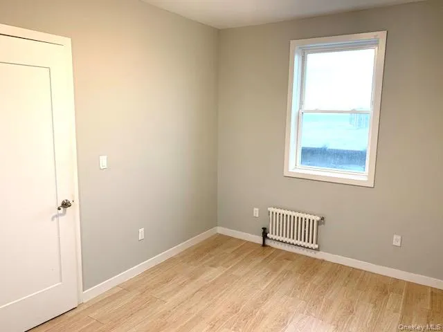 Spare room with radiator and light wood-style flooring Spare room with radiator and light wood-style flooring
