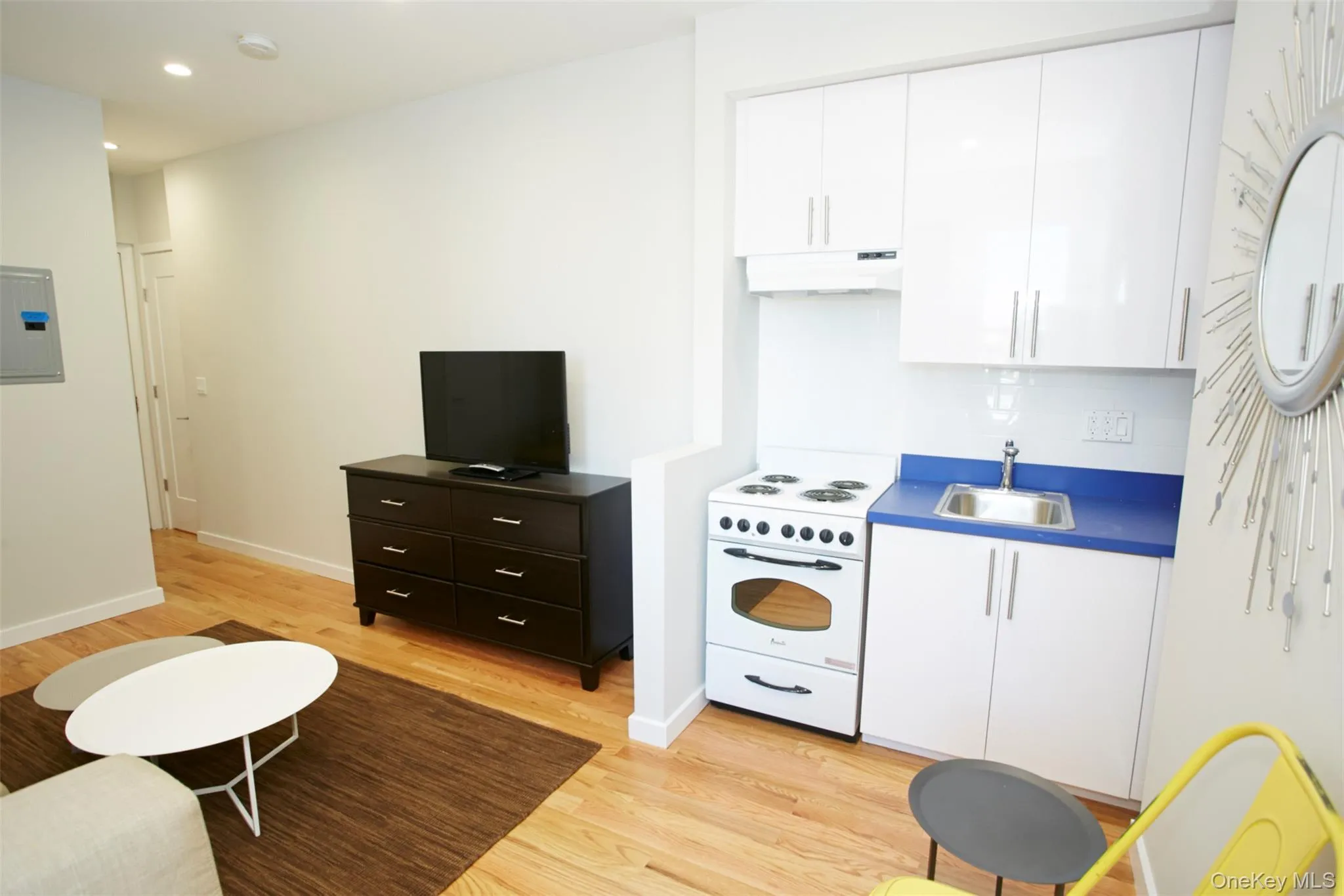 Kitchen with electric range, white cabinets, light wood-type flooring, under cabinet range hood, and recessed lighting Kitchen with electric range, white cabinets, light wood-type flooring, under cabinet range hood, and recessed lighting