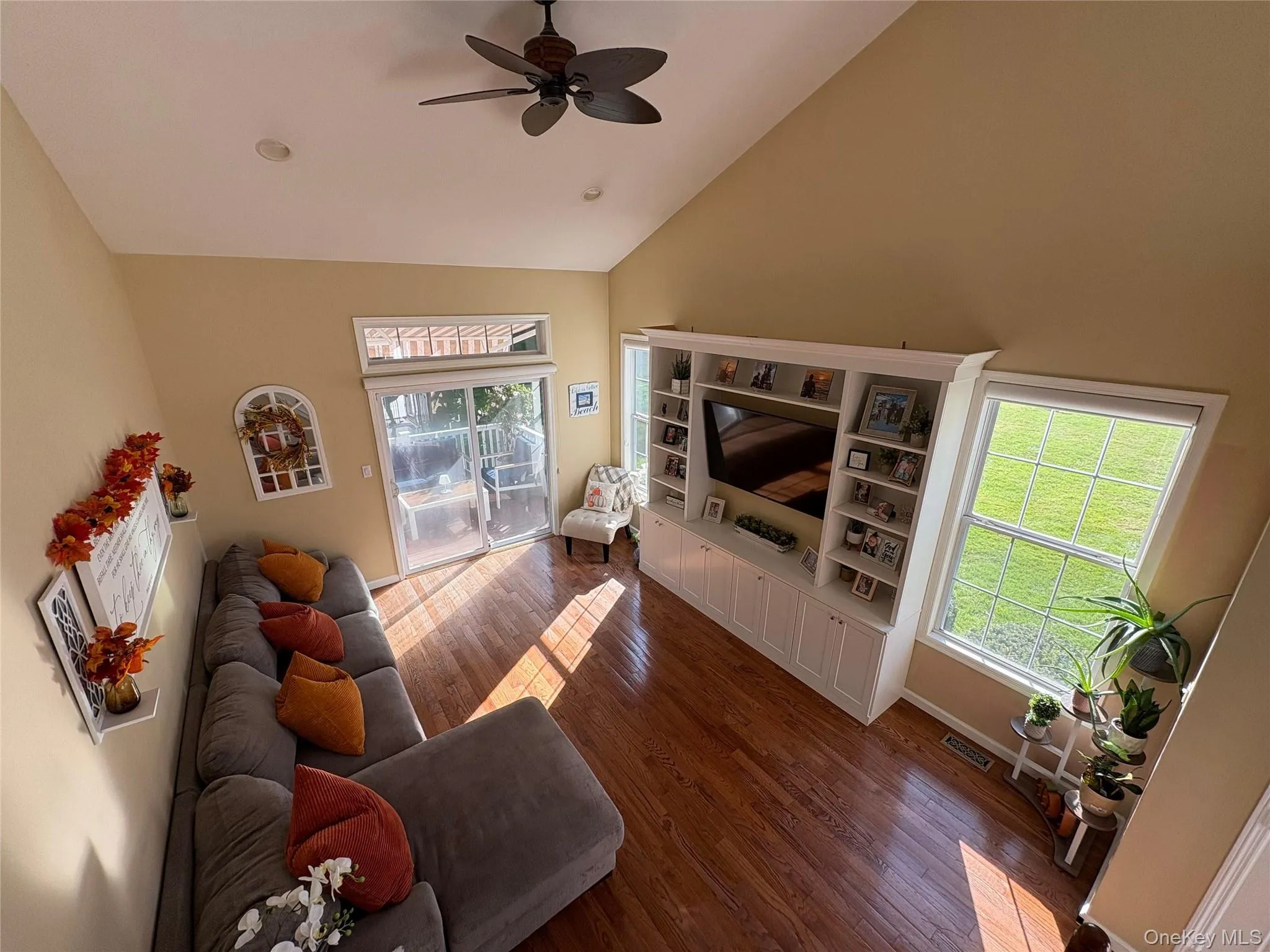 Living room with high vaulted ceiling, dark wood finished floors, and ceiling fan Living room with high vaulted ceiling, dark wood finished floors, and ceiling fan