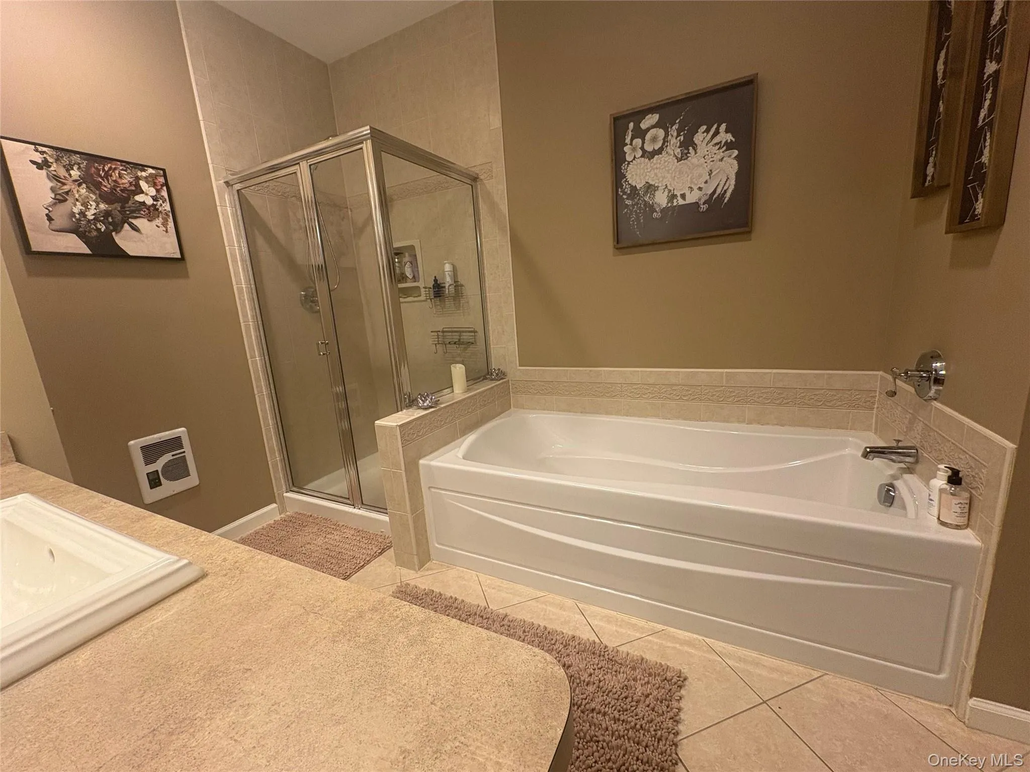 Full bathroom with light tile patterned floors, a shower stall, a garden tub, and vanity Full bathroom with light tile patterned floors, a shower stall, a garden tub, and vanity