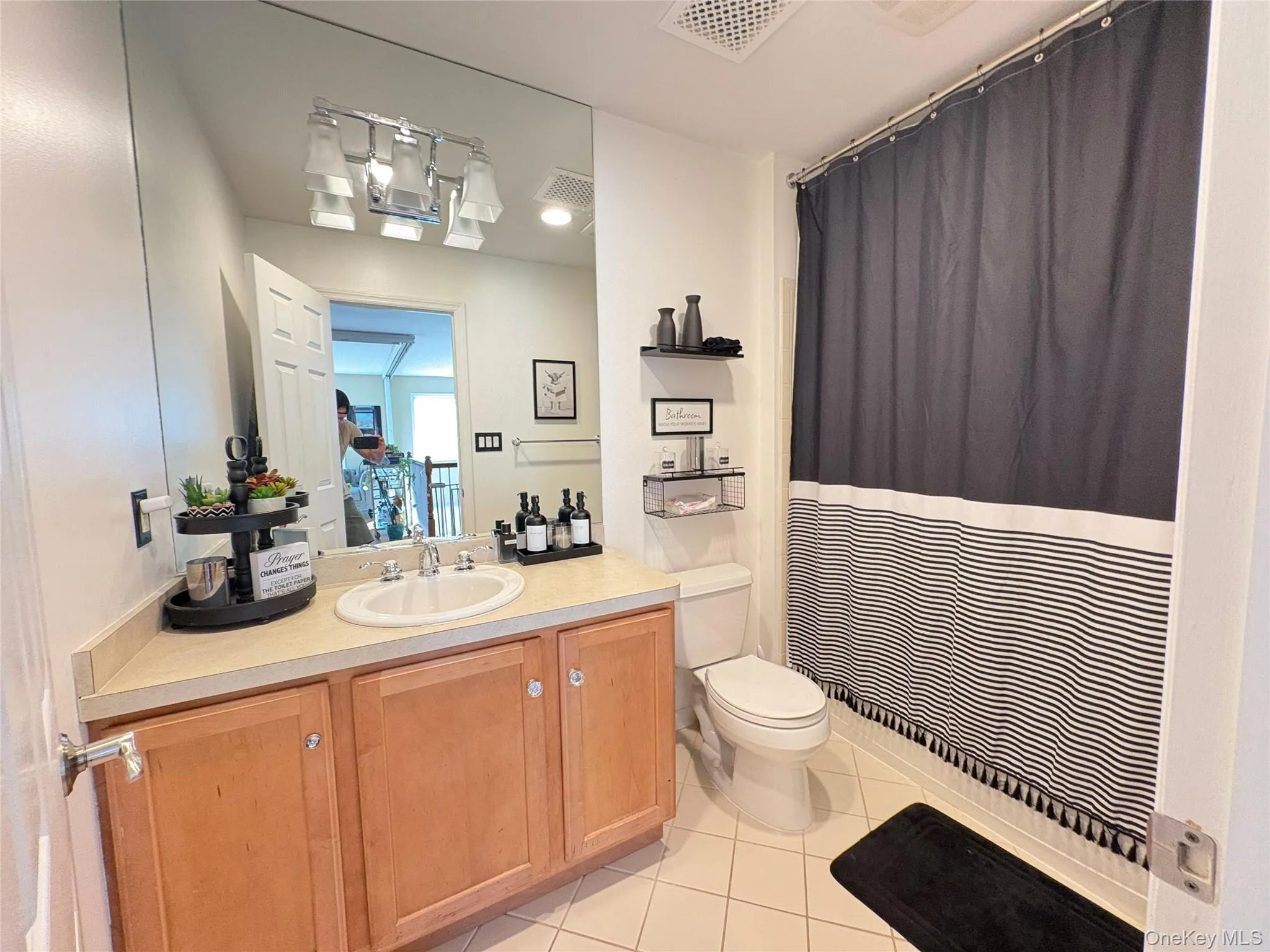 Full bathroom featuring curtained shower, light tile patterned floors, and vanity Full bathroom featuring curtained shower, light tile patterned floors, and vanity