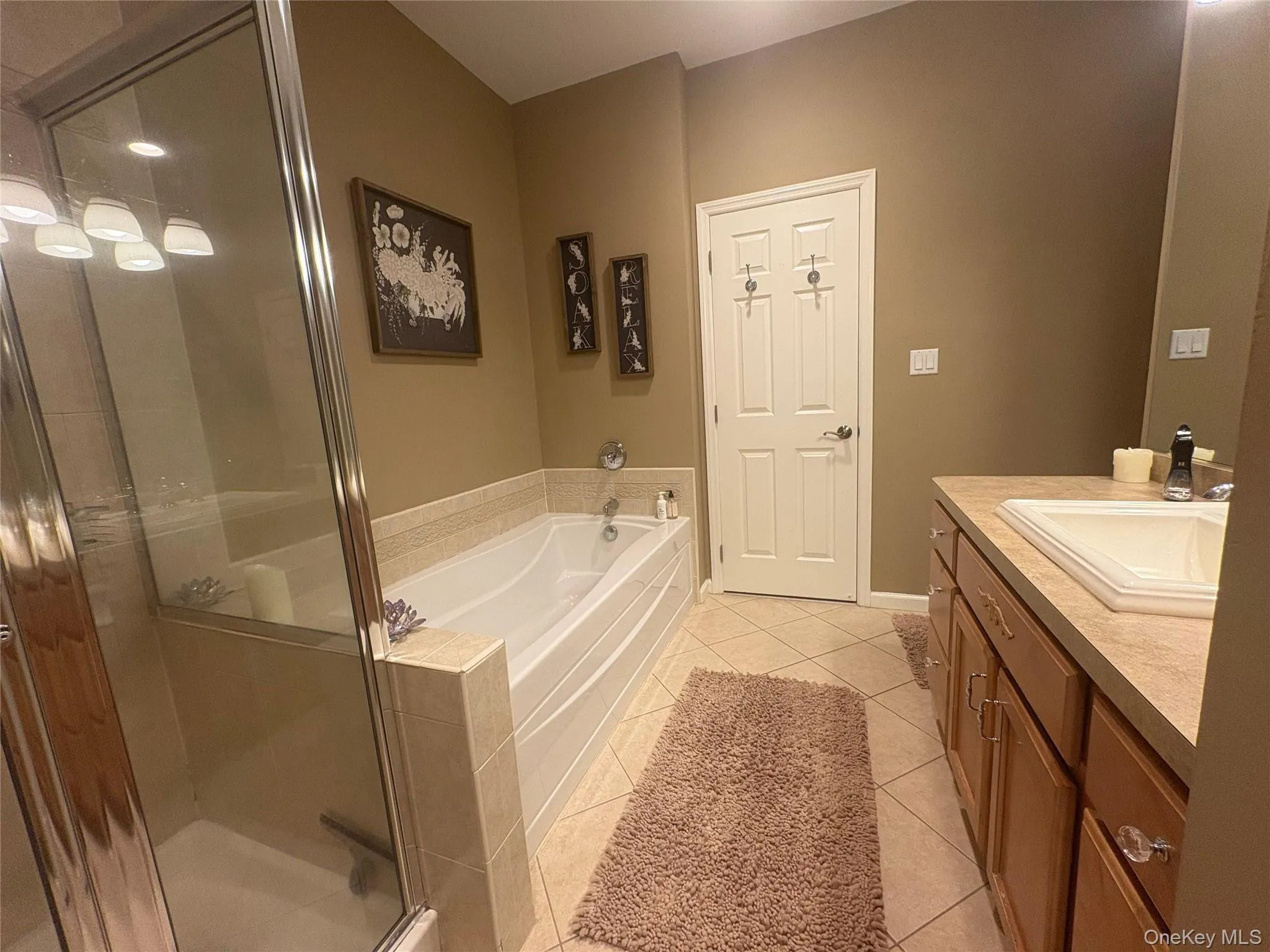 Full bathroom with light tile patterned floors, vanity, a garden tub, and a stall shower Full bathroom with light tile patterned floors, vanity, a garden tub, and a stall shower