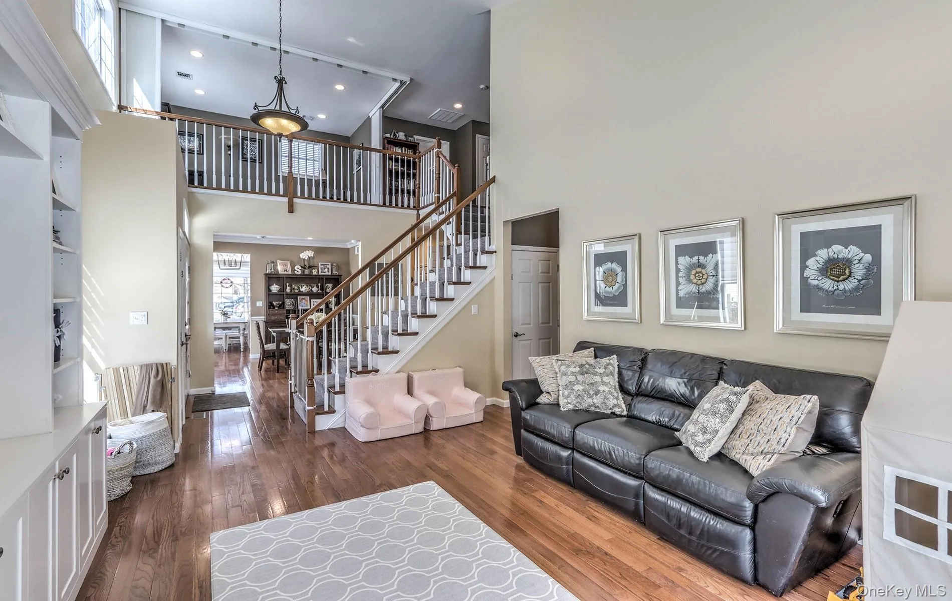 Living room with dark wood-type flooring, a towering ceiling, stairs, and recessed lighting Living room with dark wood-type flooring, a towering ceiling, stairs, and recessed lighting