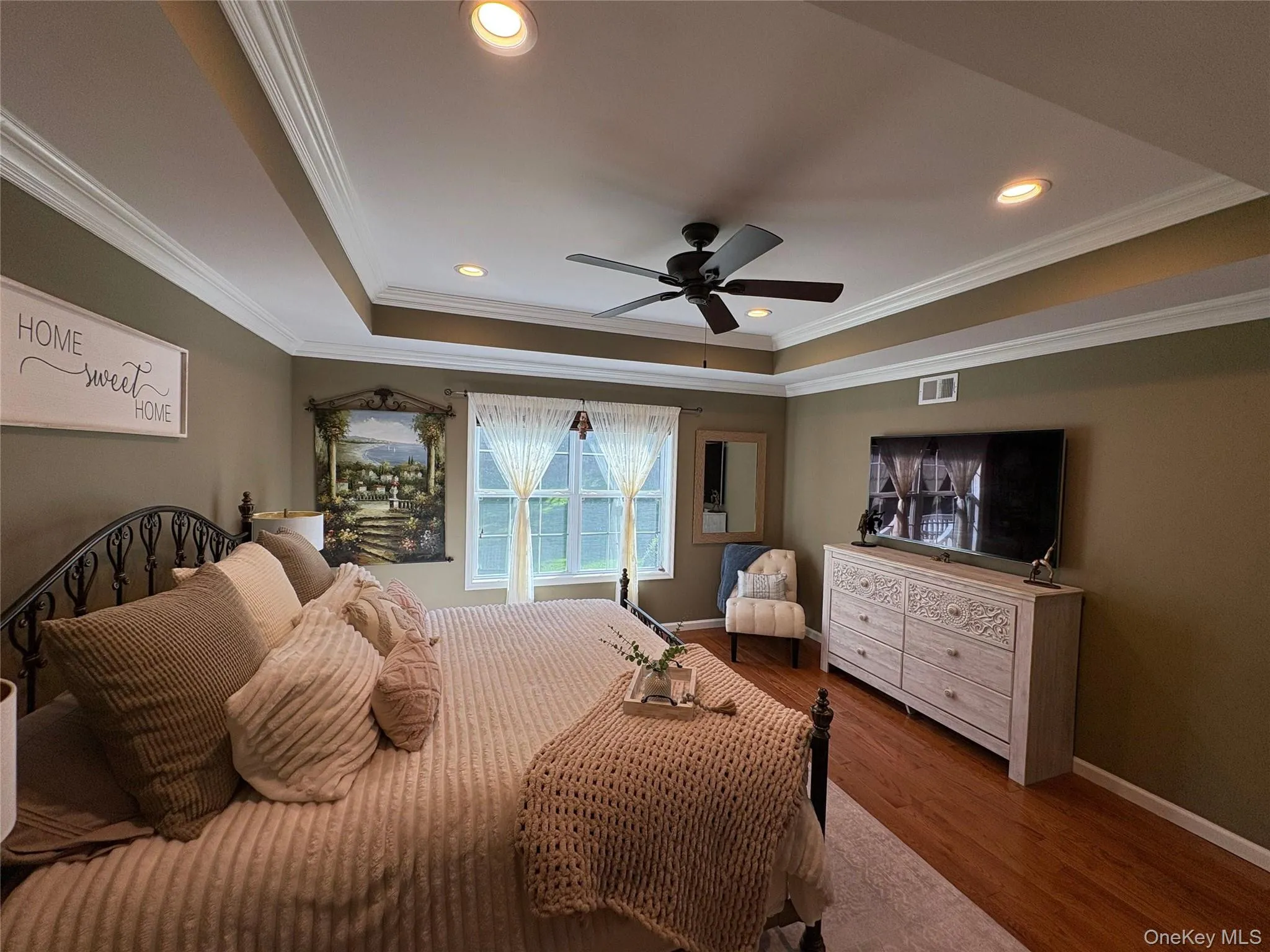 Bedroom with wood finished floors, crown molding, a raised ceiling, recessed lighting, and a ceiling fan Bedroom with wood finished floors, crown molding, a raised ceiling, recessed lighting, and a ceiling fan