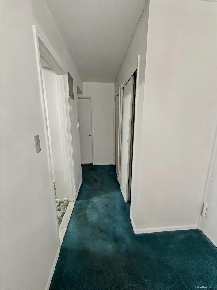 Hallway featuring dark colored carpet and baseboards Hallway featuring dark colored carpet and baseboards