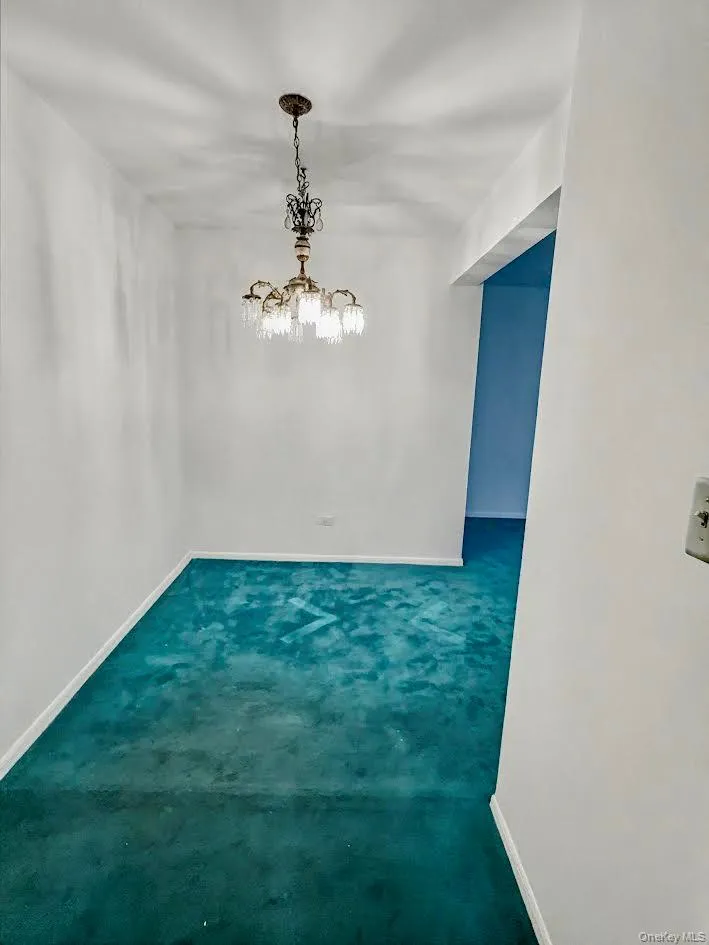 Unfurnished dining area featuring dark colored carpet and a chandelier Unfurnished dining area featuring dark colored carpet and a chandelier