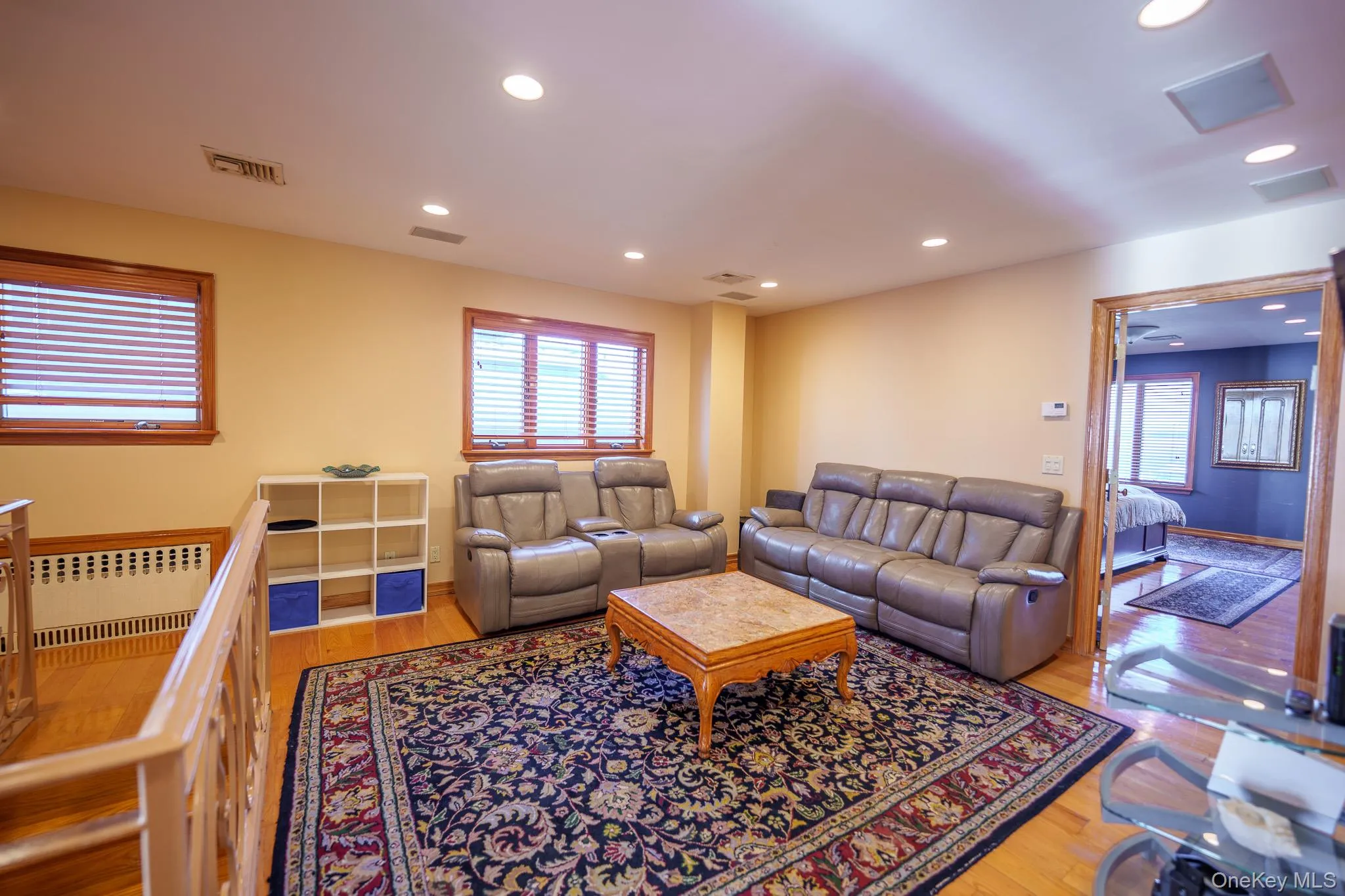 Living room featuring light wood-type flooring, radiator heating unit, and recessed lighting Living room featuring light wood-type flooring, radiator heating unit, and recessed lighting