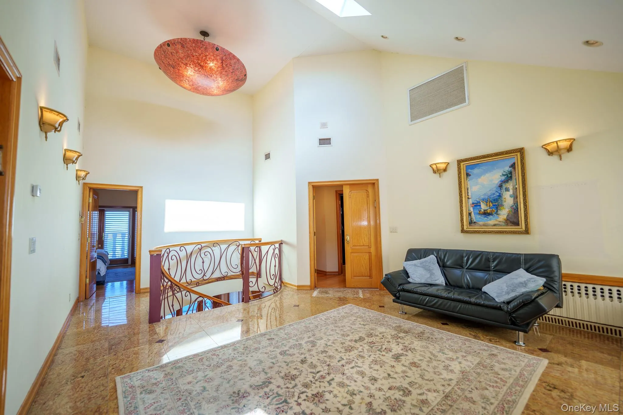 Living room with high vaulted ceiling, radiator, and a skylight Living room with high vaulted ceiling, radiator, and a skylight