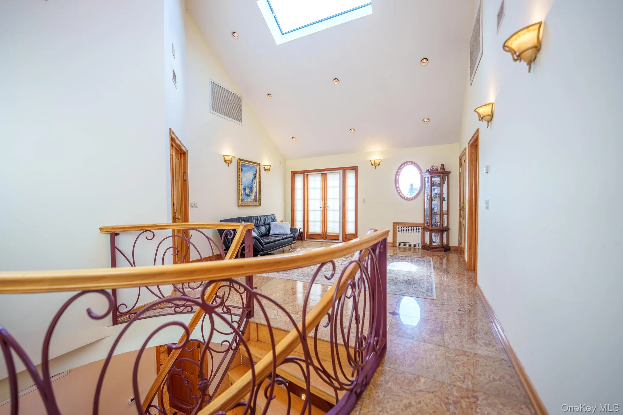 Hallway featuring a skylight, high vaulted ceiling, an upstairs landing, and radiator Hallway featuring a skylight, high vaulted ceiling, an upstairs landing, and radiator