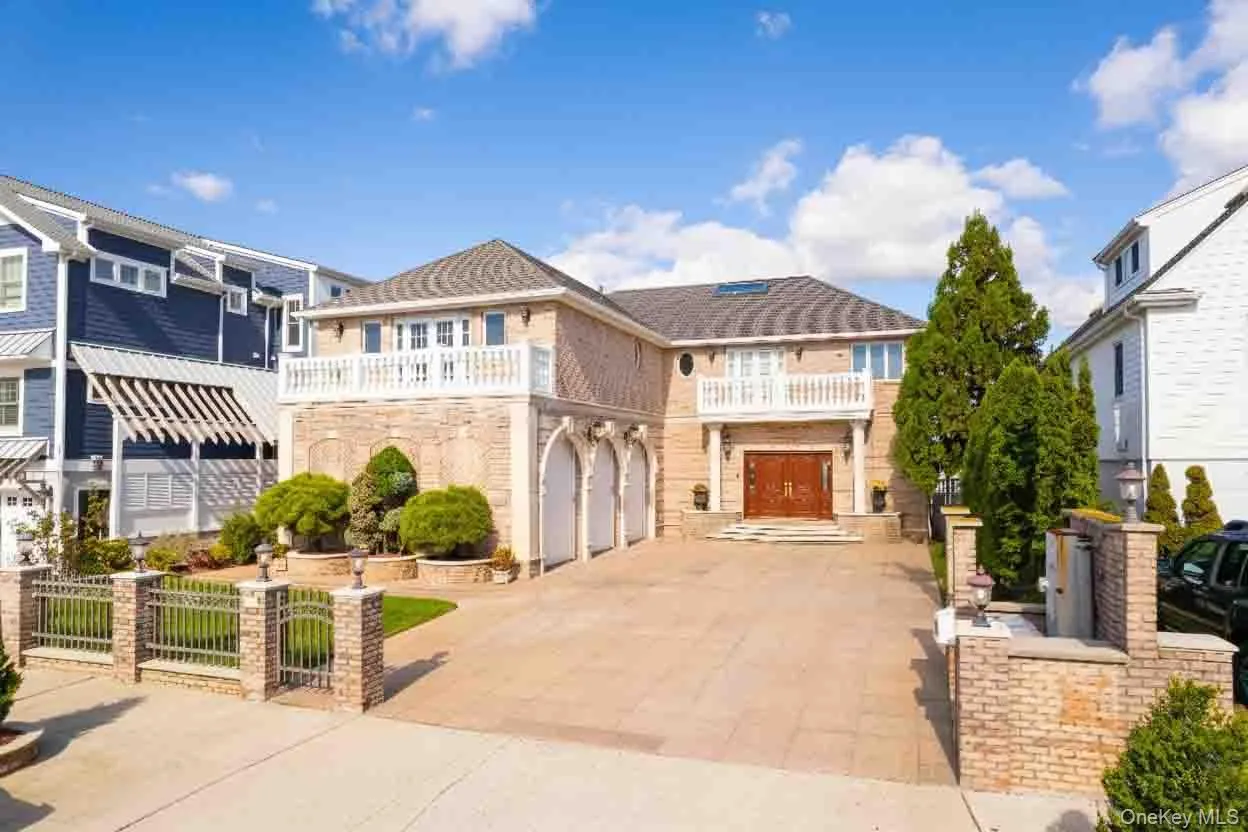 View of front of property with a balcony, driveway, a gate, stone siding, and a garage View of front of property with a balcony, driveway, a gate, stone siding, and a garage