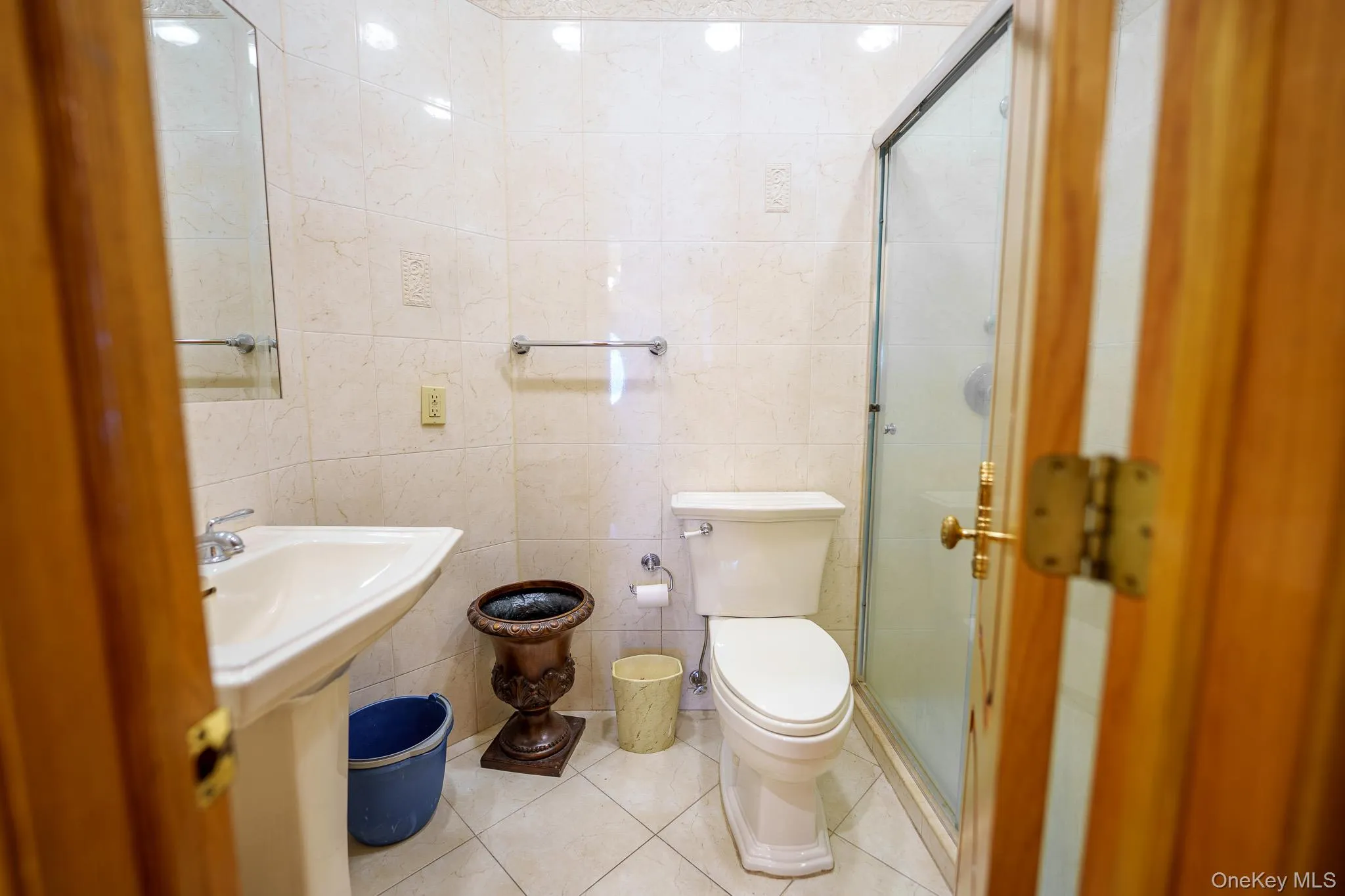 Bathroom with tile patterned flooring, tile walls, and a shower stall Bathroom with tile patterned flooring, tile walls, and a shower stall