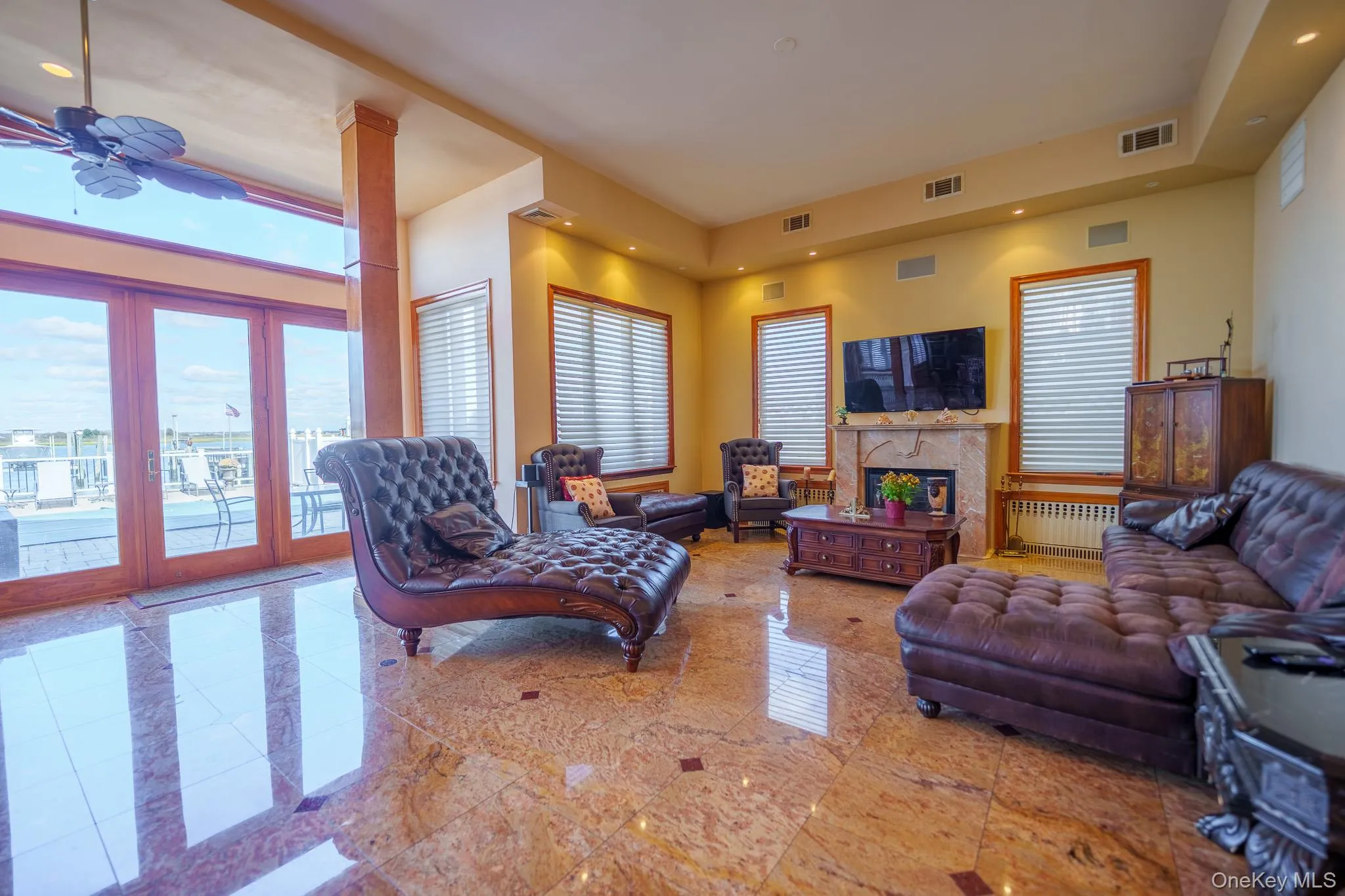 Living area featuring recessed lighting, a glass covered fireplace, radiator heating unit, and ceiling fan Living area featuring recessed lighting, a glass covered fireplace, radiator heating unit, and ceiling fan