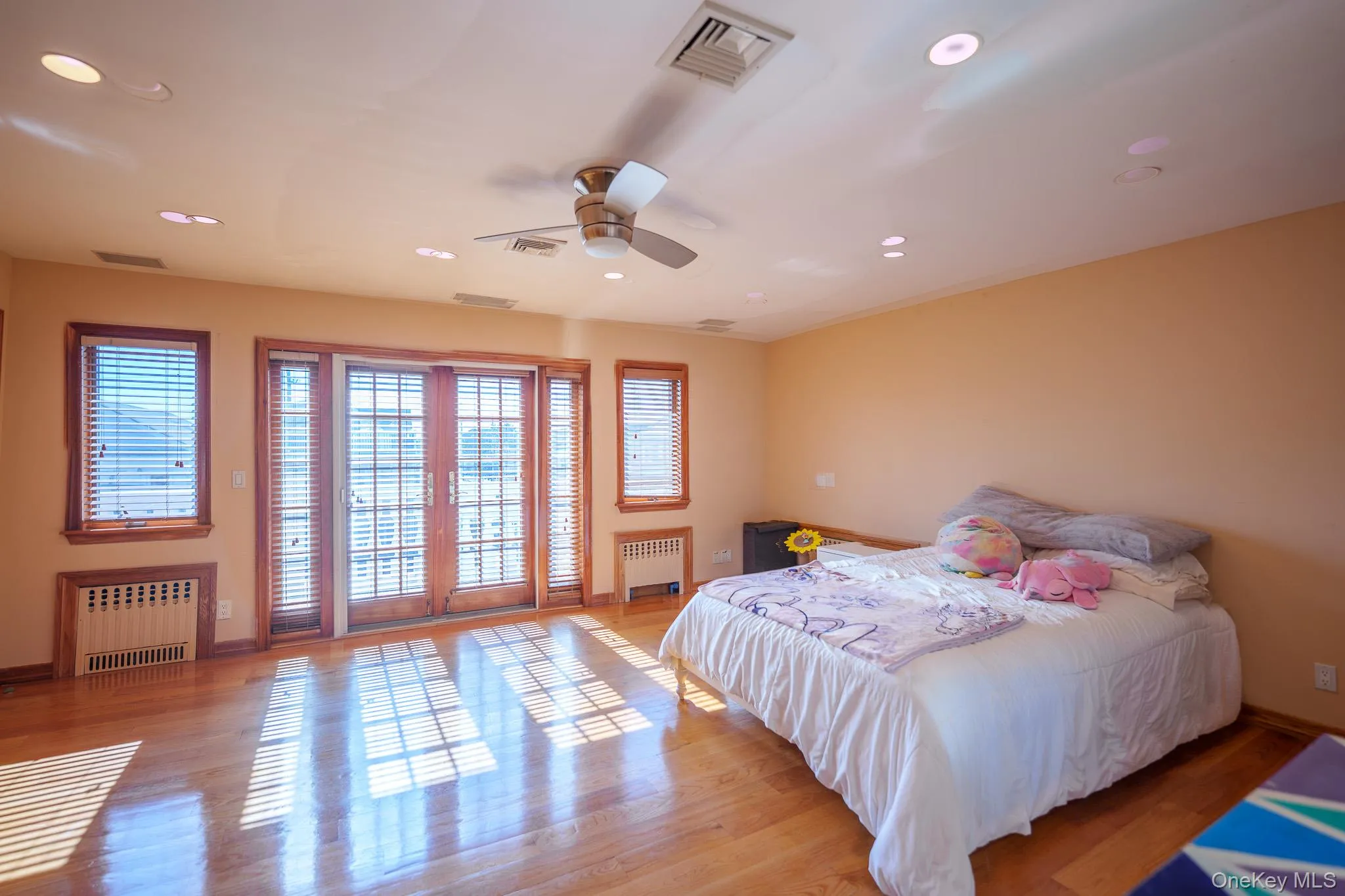 Bedroom with access to outside, radiator heating unit, recessed lighting, wood finished floors, and ceiling fan Bedroom with access to outside, radiator heating unit, recessed lighting, wood finished floors, and ceiling fan