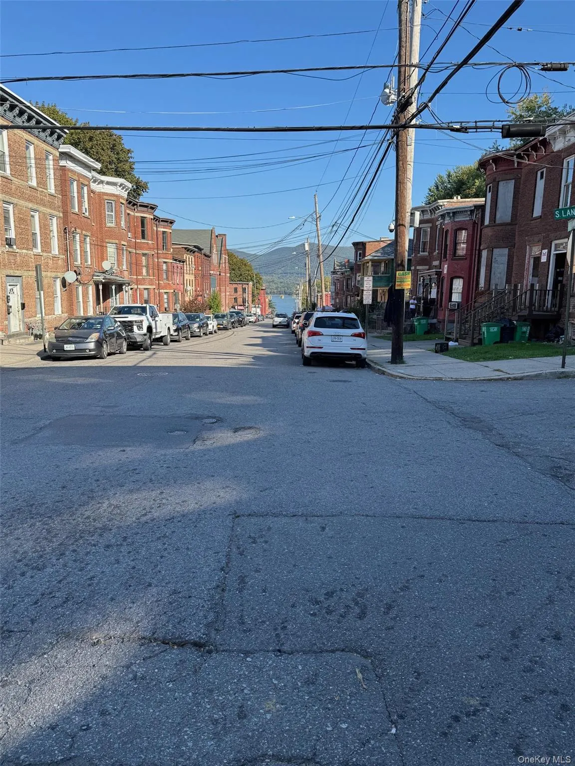 View of asphalt road with sidewalks, street lights, a residential view, and curbs View of asphalt road with sidewalks, street lights, a residential view, and curbs