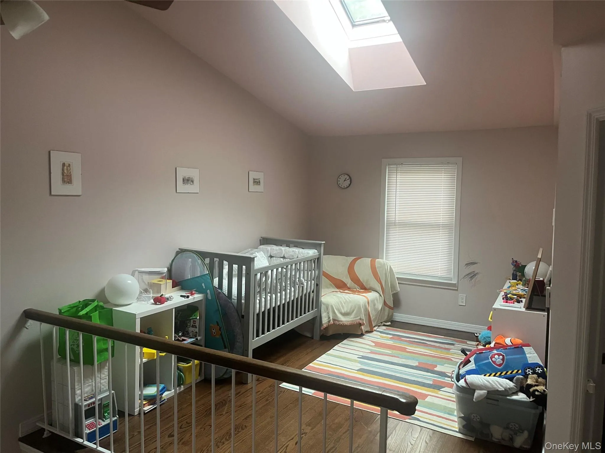 Bedroom with wood finished floors, lofted ceiling, a skylight, and a nursery area Bedroom with wood finished floors, lofted ceiling, a skylight, and a nursery area