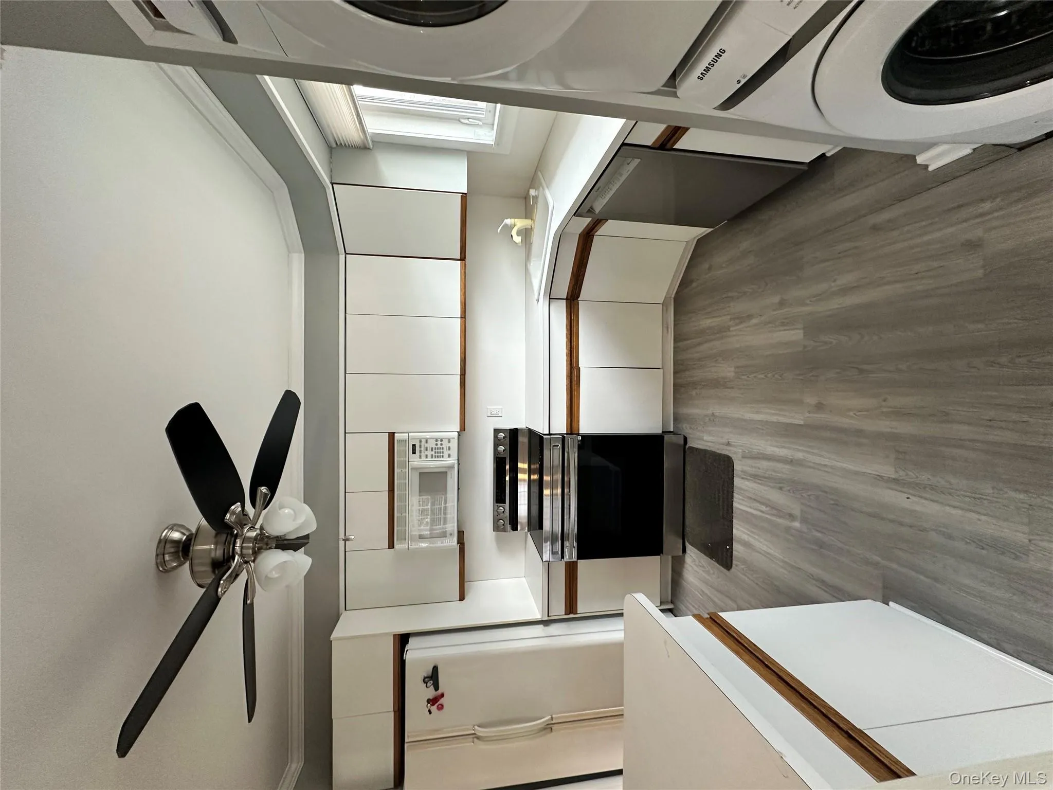 Kitchen with white cabinetry, white appliances, light countertops, dark wood finished floors, and crown molding Kitchen with white cabinetry, white appliances, light countertops, dark wood finished floors, and crown molding