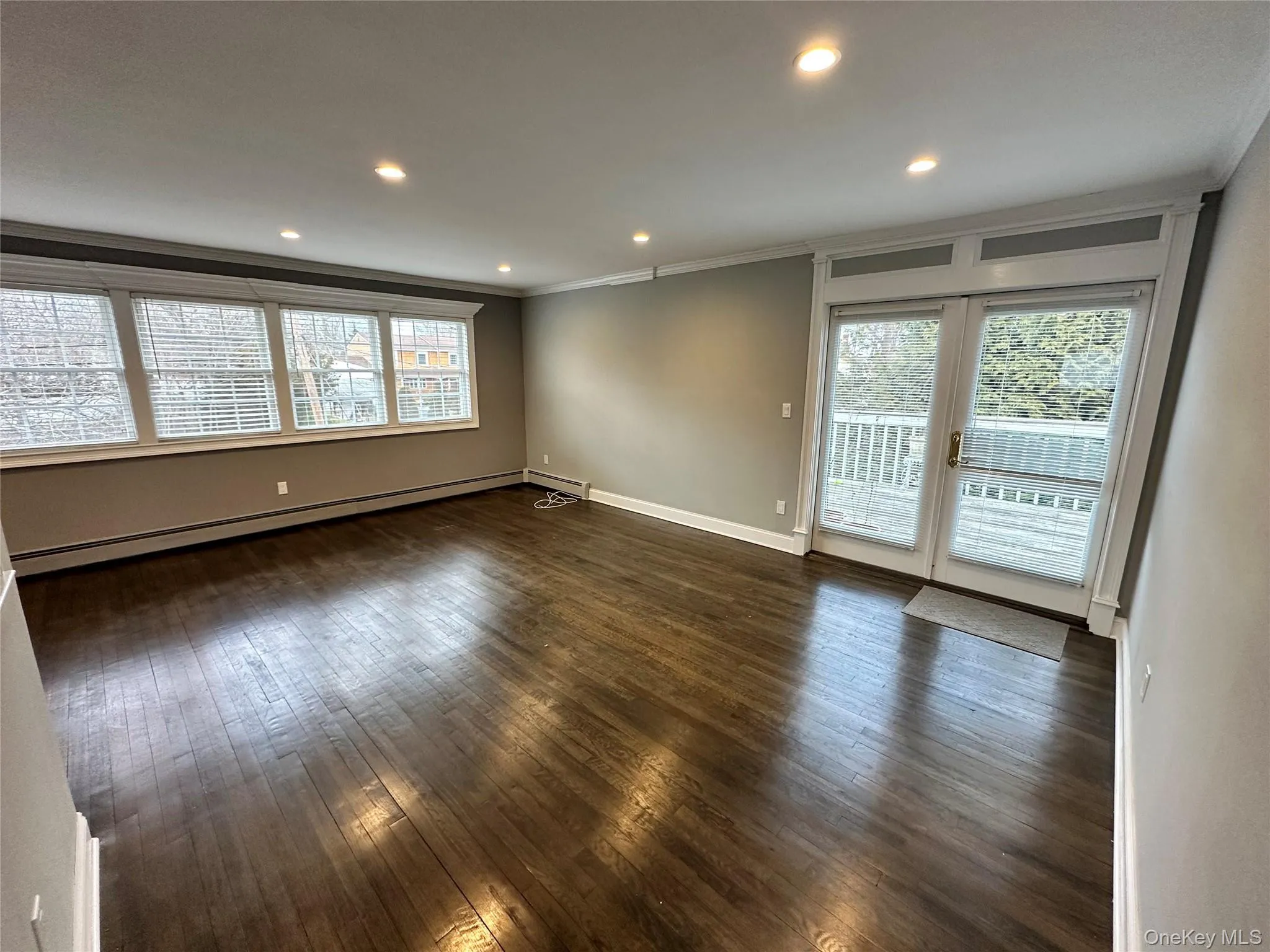Empty room with dark wood-type flooring, recessed lighting, baseboard heating, french doors, and crown molding Empty room with dark wood-type flooring, recessed lighting, baseboard heating, french doors, and crown molding