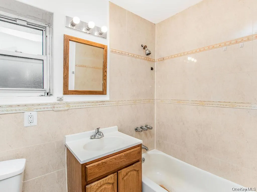 Bathroom with shower / washtub combination, vanity, and tile walls Bathroom with shower / washtub combination, vanity, and tile walls