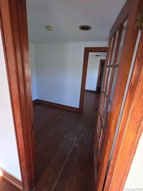 Hallway featuring baseboards and dark wood-style flooring Hallway featuring baseboards and dark wood-style flooring