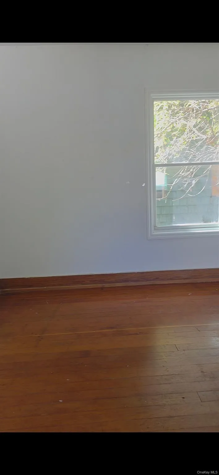 Empty room featuring baseboards and dark wood-type flooring Empty room featuring baseboards and dark wood-type flooring