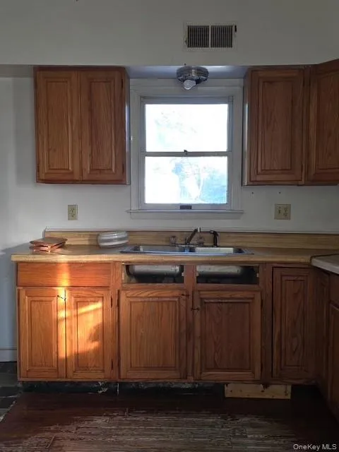 Kitchen featuring light countertops, brown cabinetry, and dark wood-style floors Kitchen featuring light countertops, brown cabinetry, and dark wood-style floors