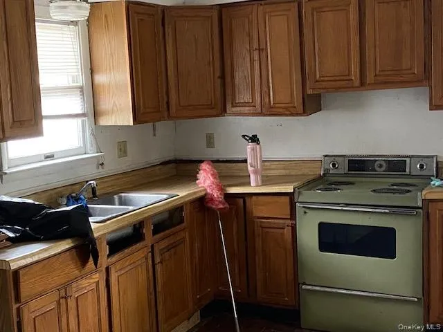Kitchen with range with electric stovetop, brown cabinets, and light countertops Kitchen with range with electric stovetop, brown cabinets, and light countertops