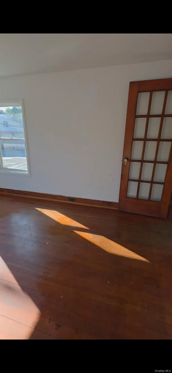 Unfurnished room featuring baseboards and dark wood-style flooring Unfurnished room featuring baseboards and dark wood-style flooring