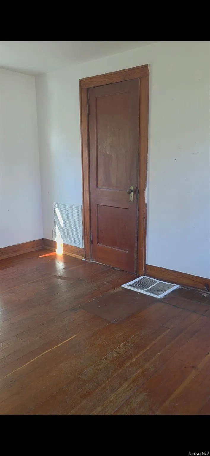 Spare room with baseboards and dark wood-style flooring Spare room with baseboards and dark wood-style flooring