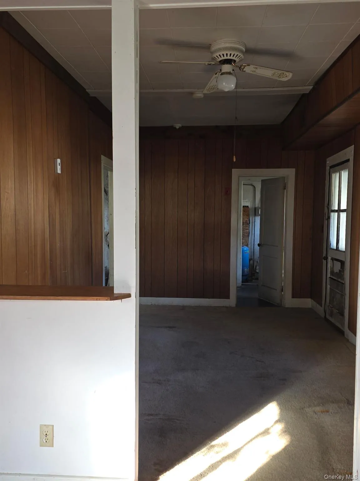 Carpeted spare room with wood walls and a ceiling fan Carpeted spare room with wood walls and a ceiling fan