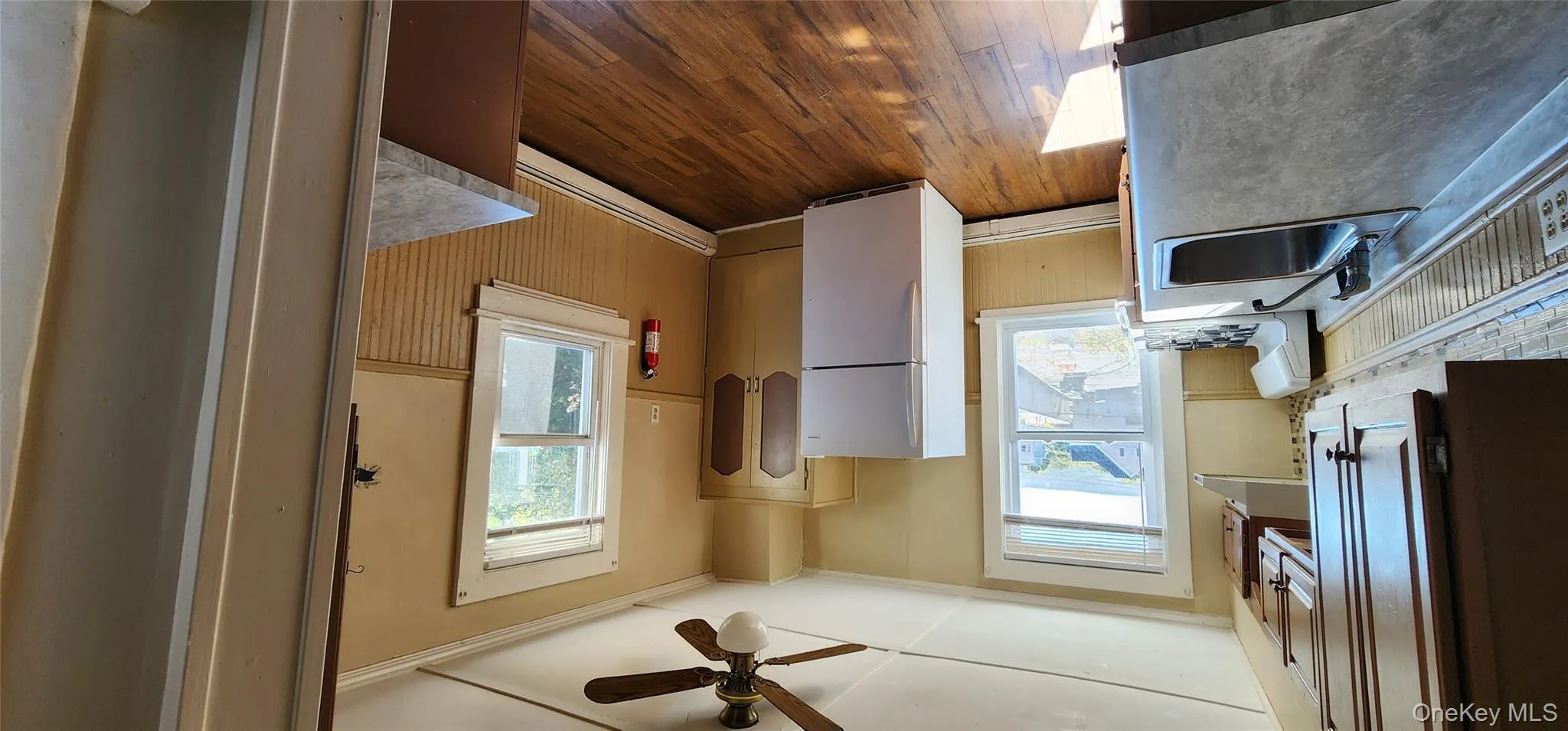 Kitchen with fridge, wainscoting, stove, crown molding, and dark wood-style floors Kitchen with fridge, wainscoting, stove, crown molding, and dark wood-style floors